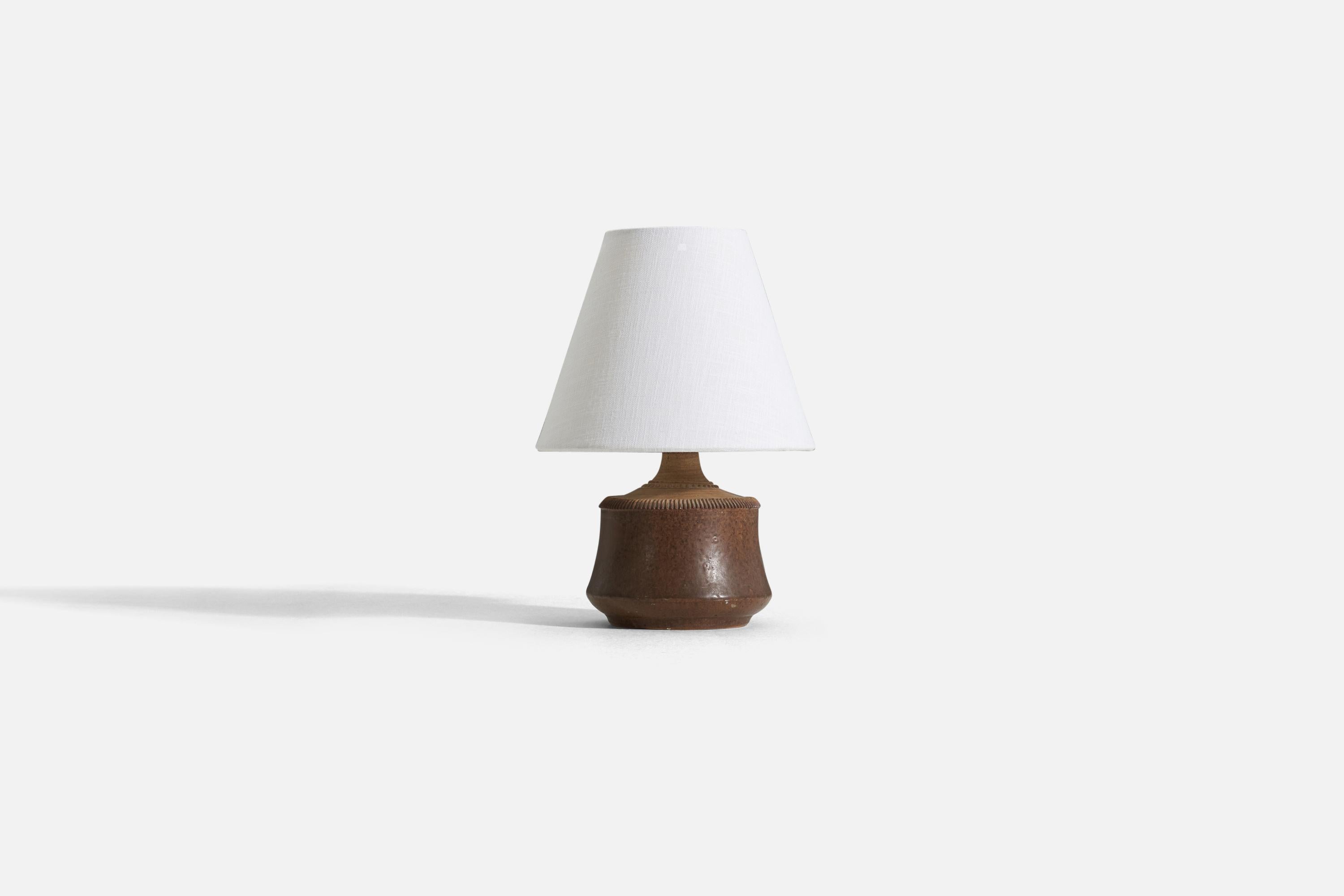 A brown stoneware table lamp with simple incised decor, by Klase Höganäs. Signed. 

Measurements listed are of the lamp itself. Sold without lampshade.
For reference:
Measurements of shade (inches) : 4 x 8 x 6.5 (T x B x S)
Measurements with