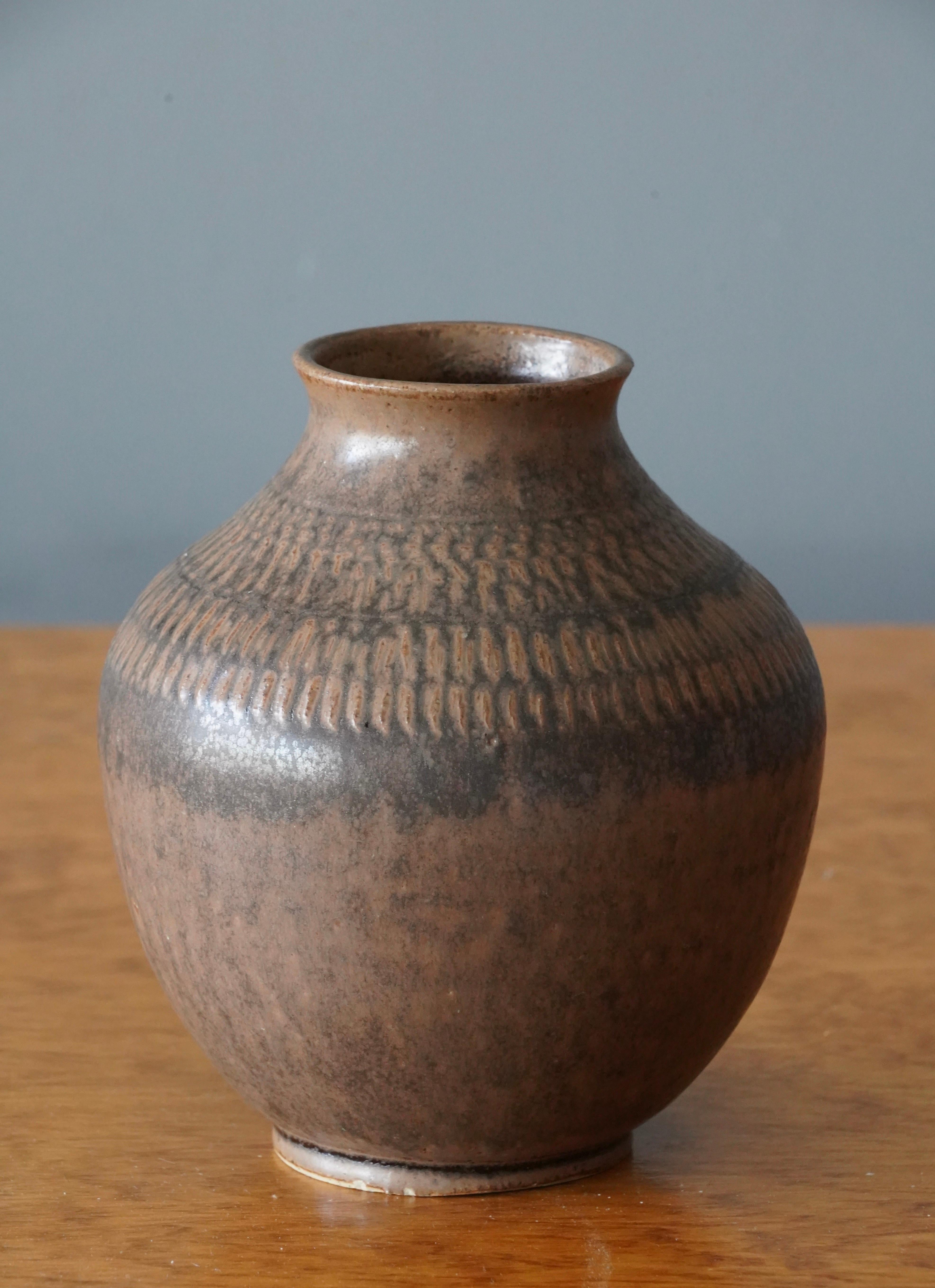 A vase by Klase Höganäs. In brown-glazed stoneware. Signed. Features a highly artistic glaze and simple incised ornamentation.

 