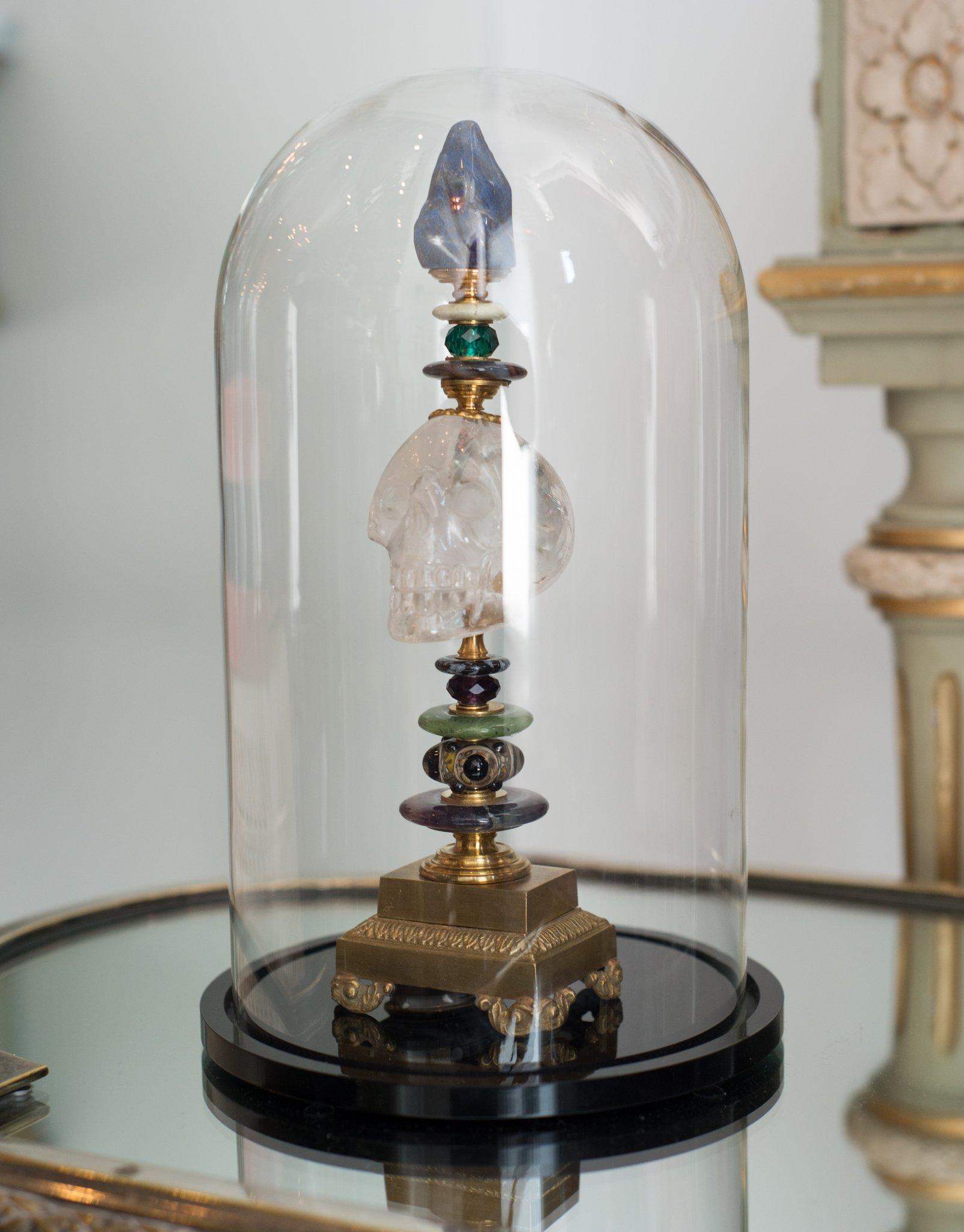 A one of a kind sculptural objet consisting of a carved rock crystal skull with semi-precious stones combined with antique bronze components on a pedestal by German artist, Dupont.

Klaus Dupont’s stylistically unique works are inspired by his