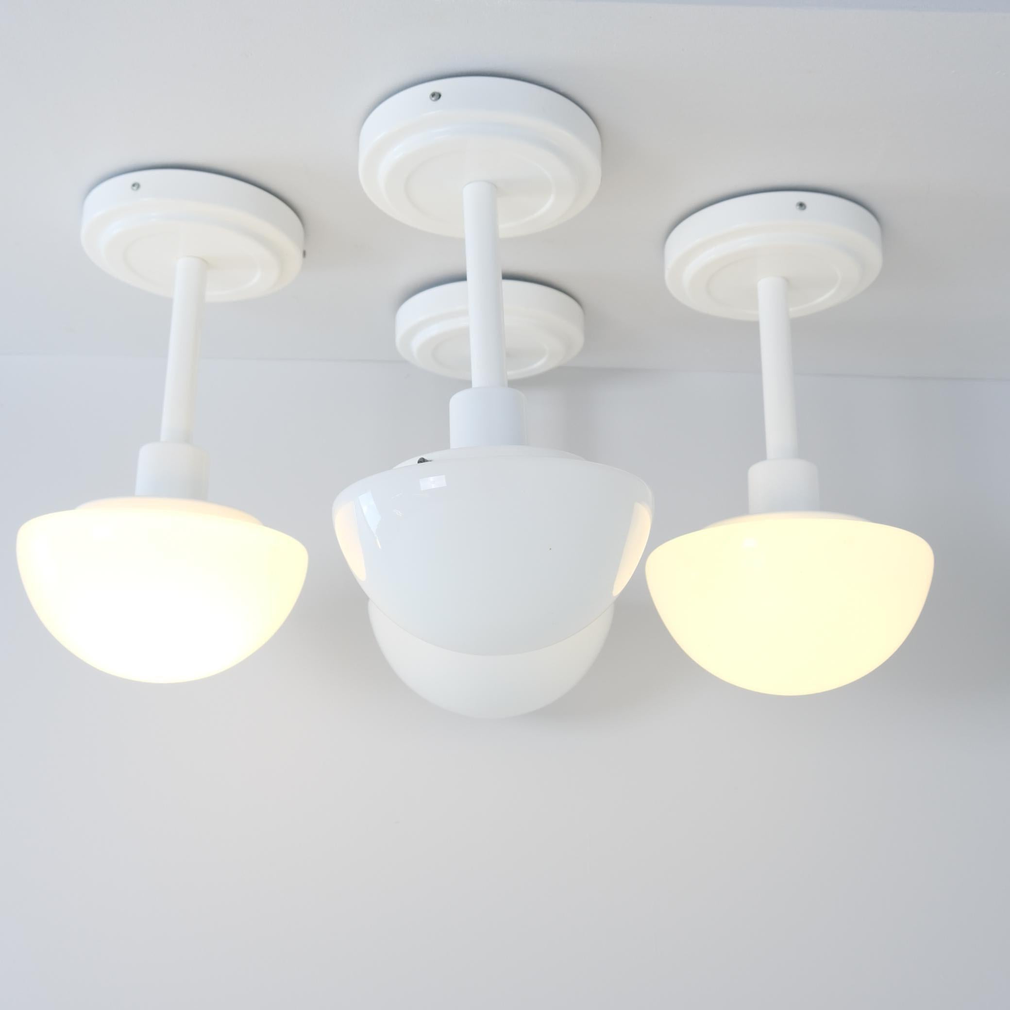 Ein Satz von vier Deckenleuchten Modell 5574 von einem der führenden Designer der zweiten Generation in Orno Klaus Michalik aus seiner klassischen Serie Bau. Die Lampen sind minimalistisch und ganz in Weiß gehalten. Sie bestehen aus einem lackierten