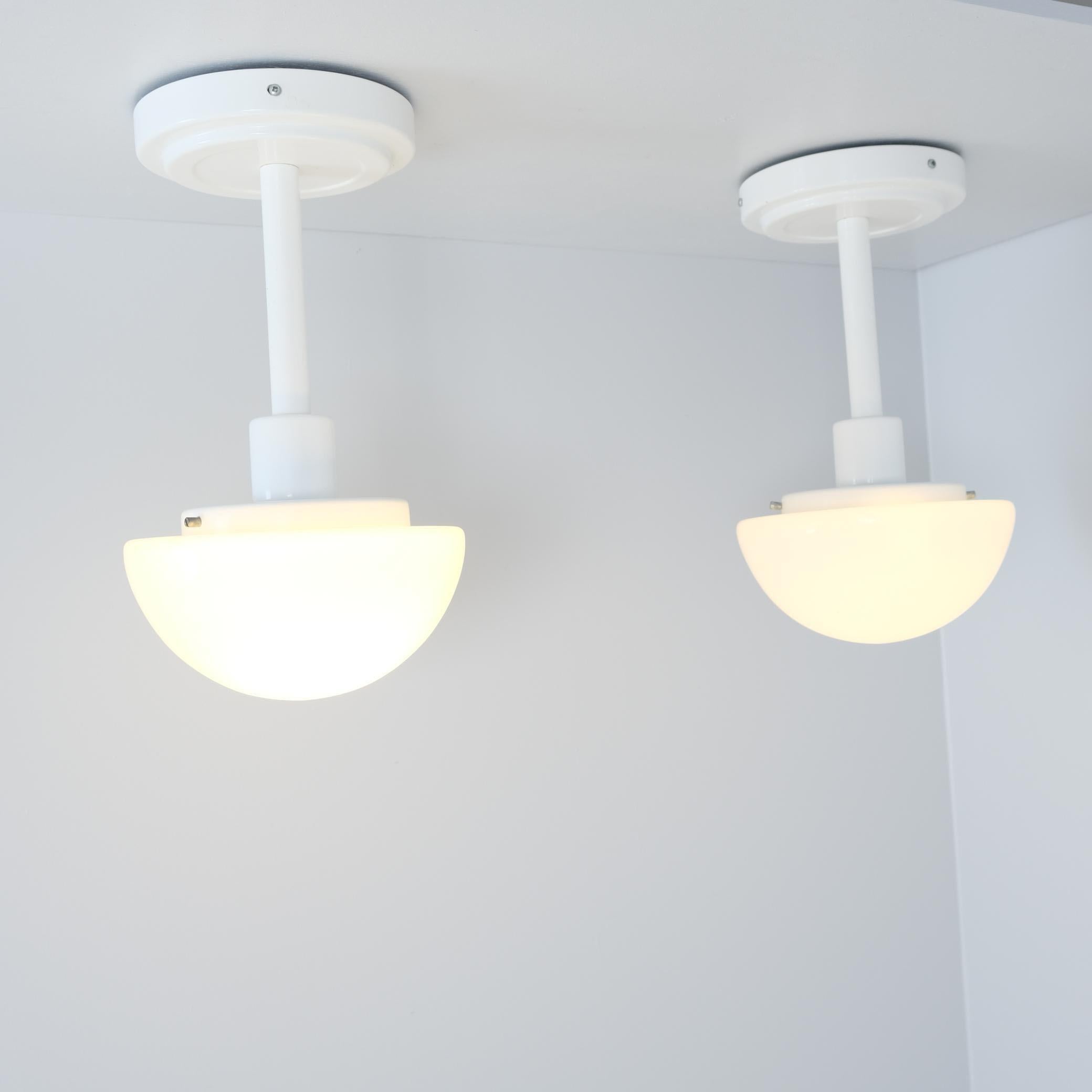 Juego de dos lámparas de techo modelo 5574 de uno de los diseñadores de segunda generación más importantes de Orno, Klaus Michalik, de su serie clásica Bau. Las lámparas son minimalistas y de color totalmente blanco, compuestas por una base de metal
