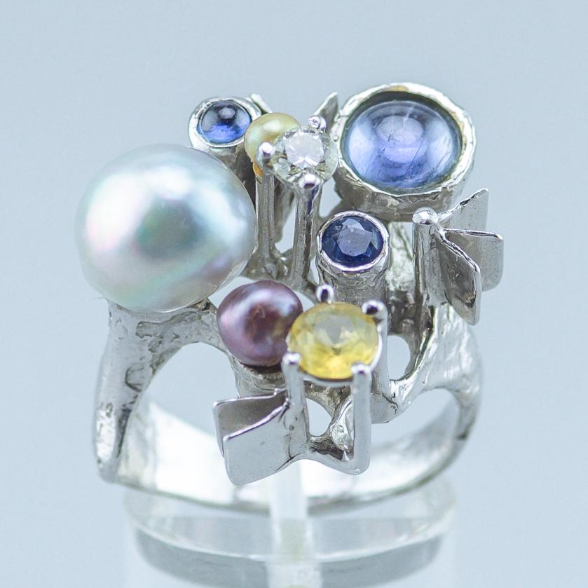 White gold ring from the German goldsmith Klaus Neubauer.
Designed in 1971.
Signed KN71.
585/14k white gold with three pearls, two topaz cabochons, one spinel, one tourmaline and one diamond.
Total 11.3 gram. 
Size: US 6.8, UK N.
Inside diameter