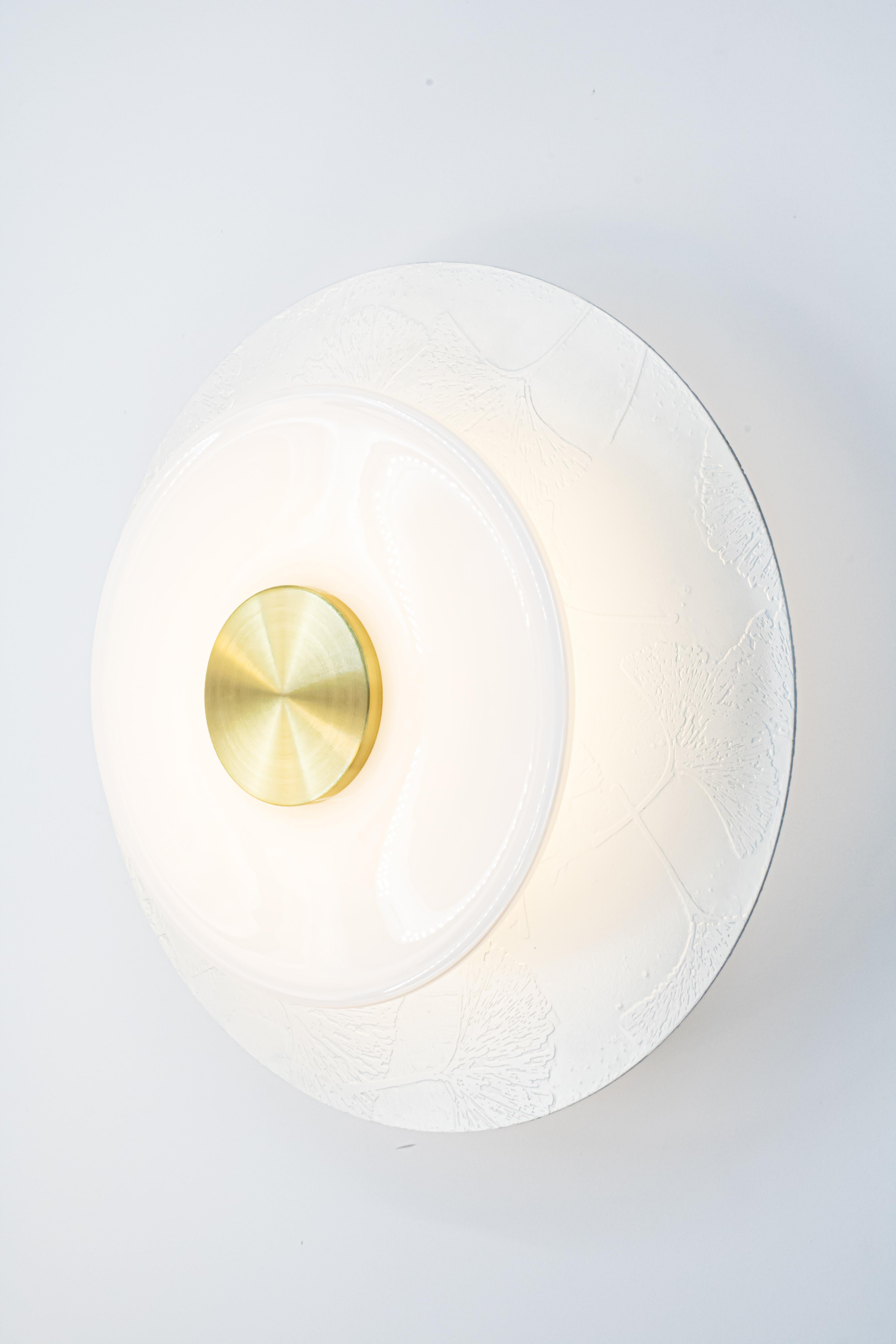 Our wall mounted Klein Sconce offers an atmospheric glow softened by a hand blown glass rondelle in the front while still giving off ample back lighting. With multiple brass textures and finishes available, the Klein Sconce can be customized in a