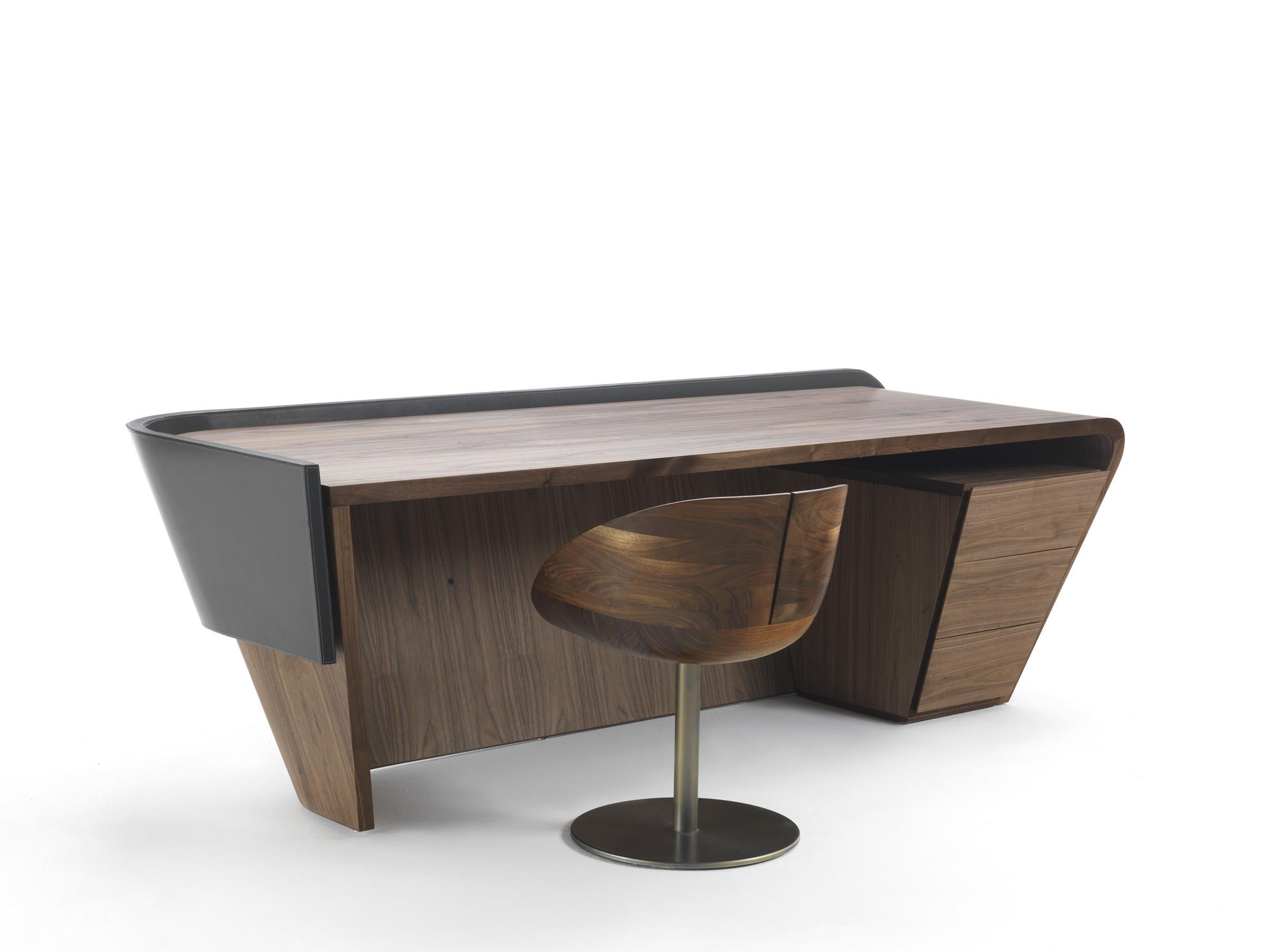 Schreibtisch aus furniertem Mehrschichtholz mit fließenden Linien, bestehend aus einer gebogenen Platte und einer Frontplatte, die entweder furniert oder mit Leder bezogen sein kann. Sie ist mit einer praktischen Kommode ausgestattet, die aus drei