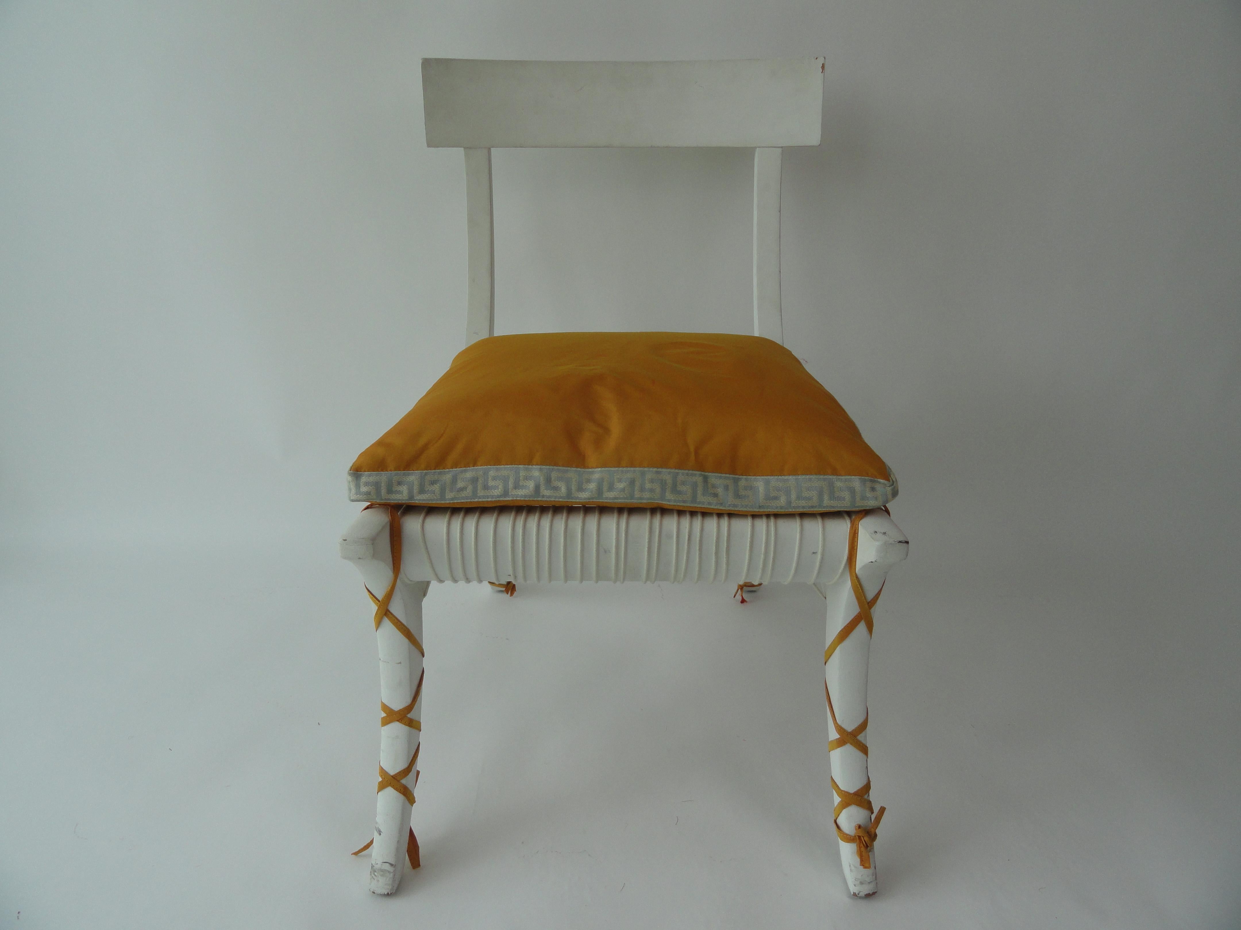 20th century, wood Klismos-style chair in white painted finish with custom cushion. Cushion has Greek key banding detail and straps that wrap around the legs. Seat has cotton cording strapping. See detail pics.