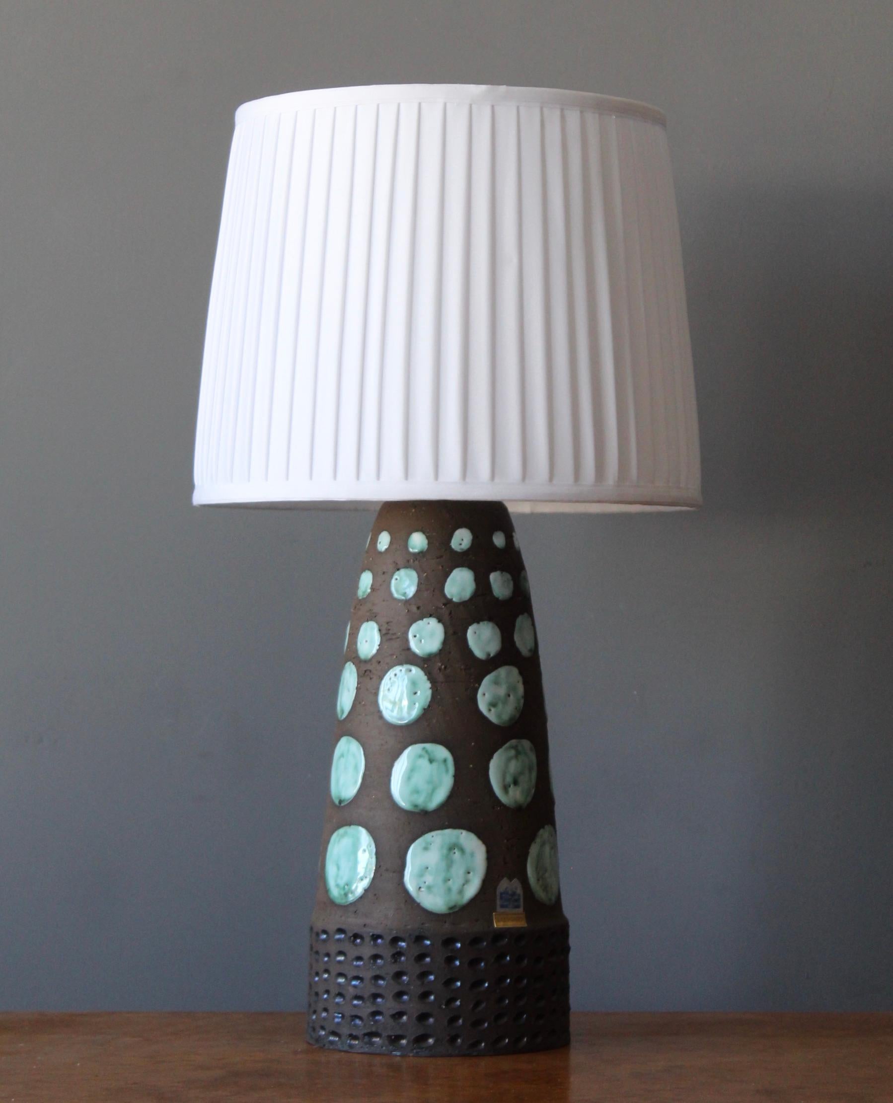 A sizable table lamp, designed and produced by Klosterkeramik, Ystad, Sweden, c. 1960s. Features semi glazed stoneware, in brown and teal / blue. With makers label. Incised details. 

Stated dimensions exclude lampshade, height includes socket.