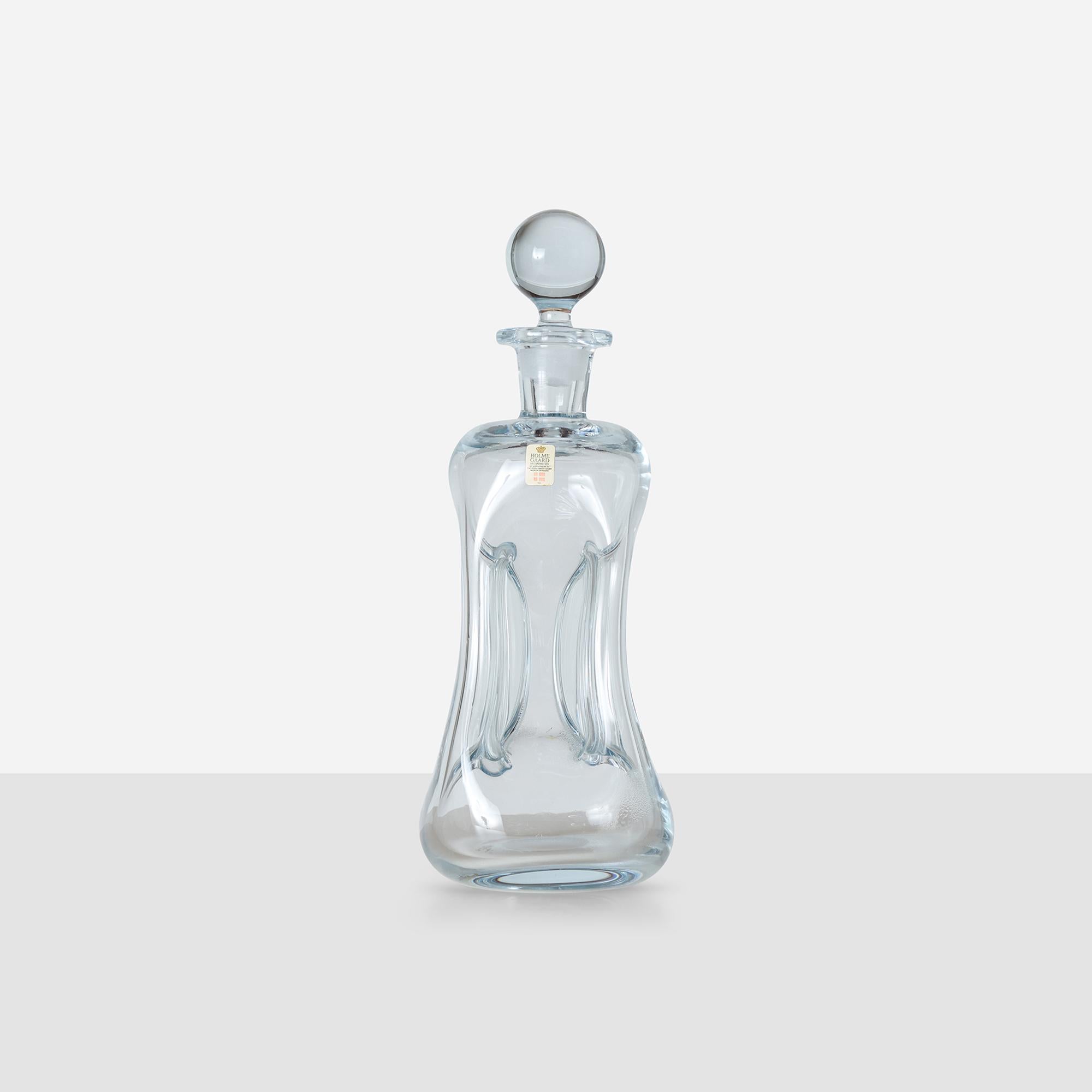 Decanter alto in vetro trasparente con lati rientranti, collo svasato e tappo originale. Prende il nome dall'allegro suono 