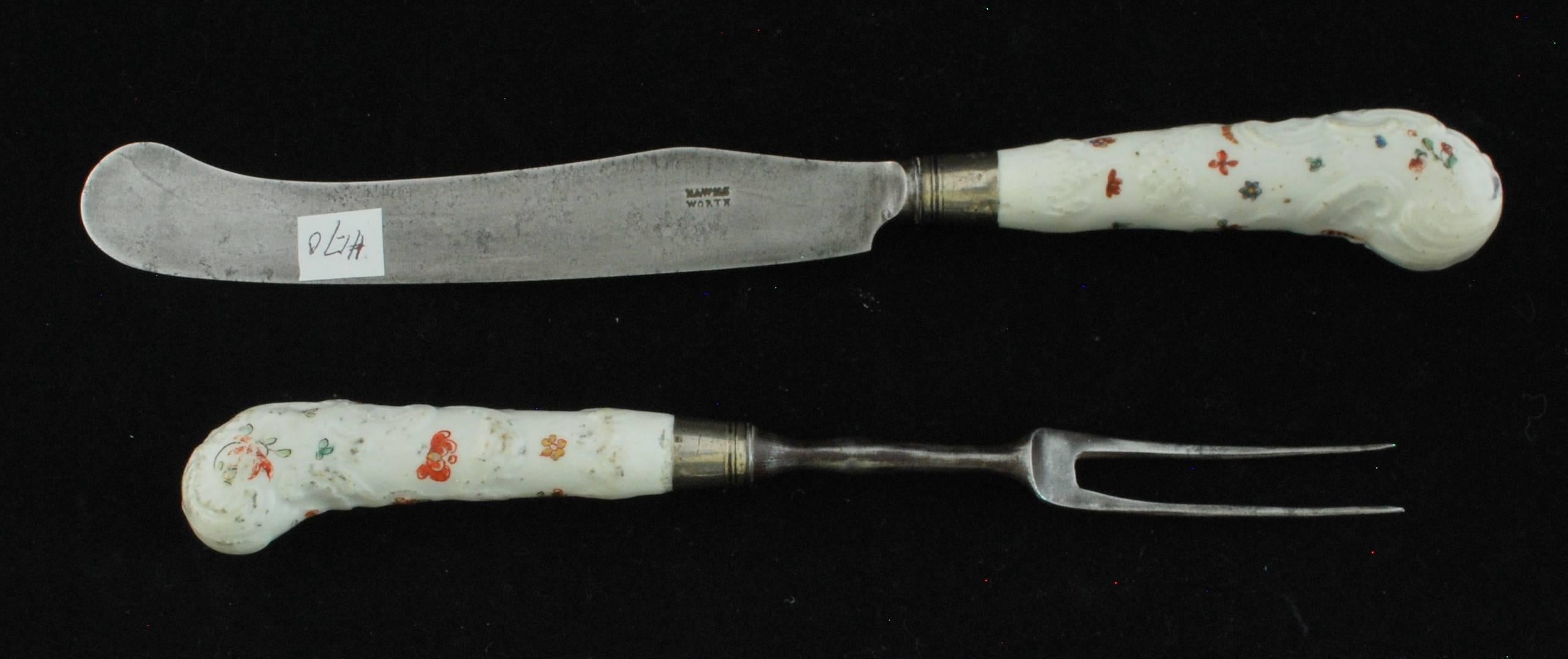 An unsually early set of handles with original steel tines and blade. Pistol grip form moulded with acanthus scrolls, leaves and swags and painted with indianische Blumen in a Kakiemon palette of iron-red, blue, green and black with gilding on