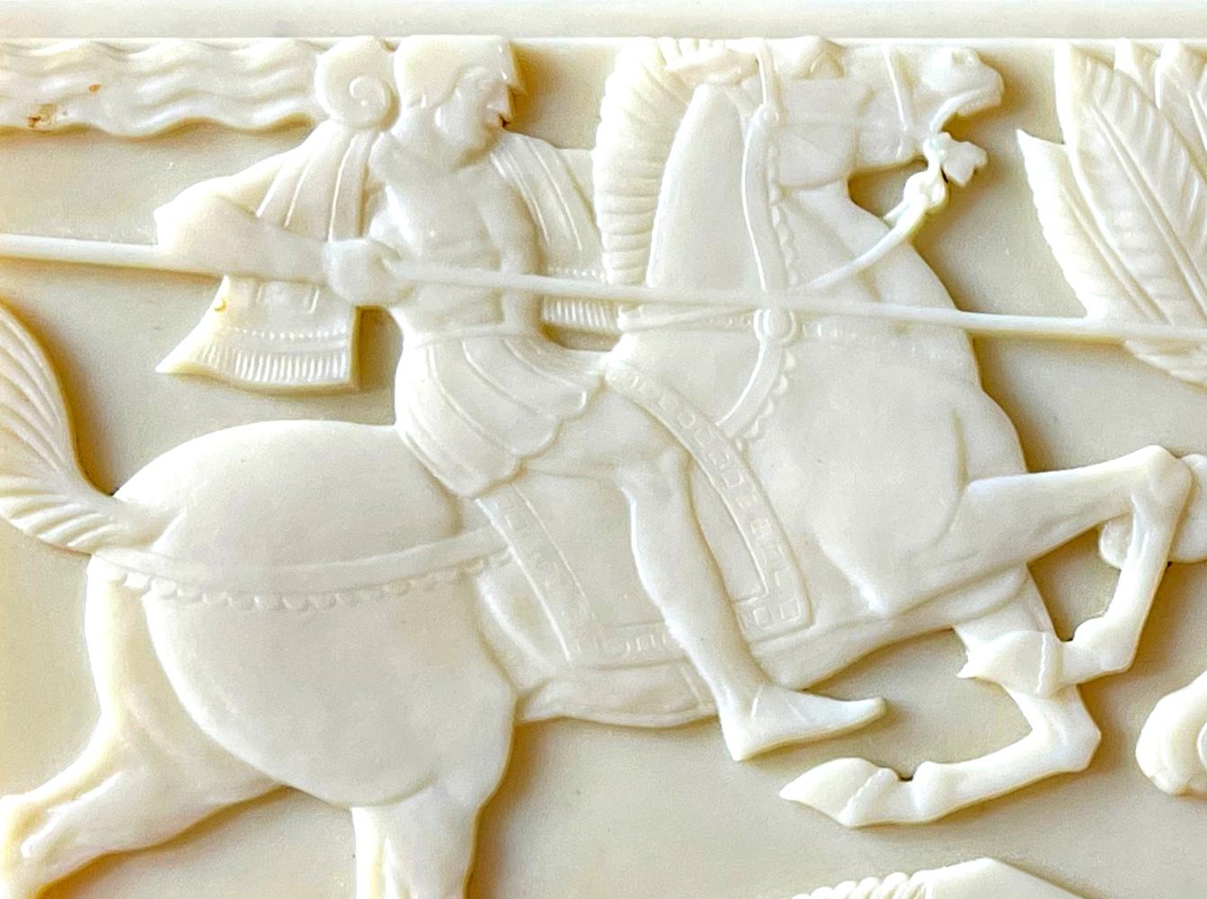 Exceedingly rare and very finely made, this Art Deco hinged box is topped with a lid in ivory-hued Bakelite that features a knight on horseback spearing a rearing lion, all in a stylized manner that draws from Medieval and Assyrian precedents. The