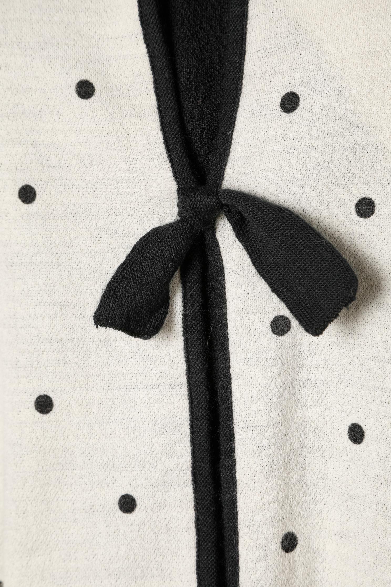 Ensemble veste et débardeur en tricot avec motif à pois. composition en tricot : 50% laine, 50% acrylique. 
Fermeture auto-agrippante sur le milieu du devant + nœud en laine. Boutons sur les poignets (1 bouton supplémentaire fourni) 
Pad d'épaule.