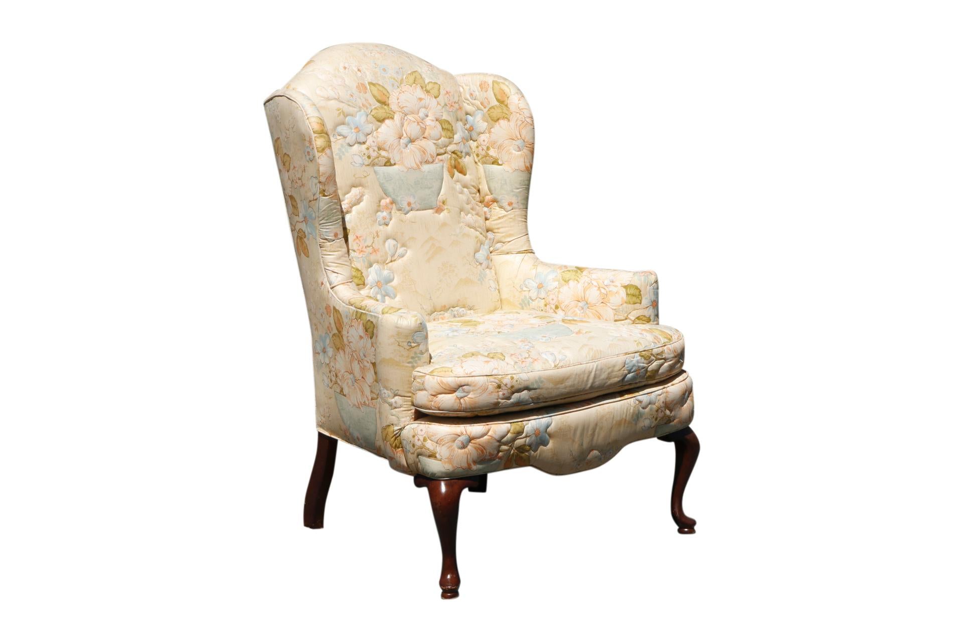 A pair of Queen Anne style wingback chairs made by Knob Creek. Upholstered throughout in a floral satin fabric with a quilted motif, framed with outward rolled arms and a serpentine skirt. Cabriole legs finish in rounded pad feet. Arm height 24.5