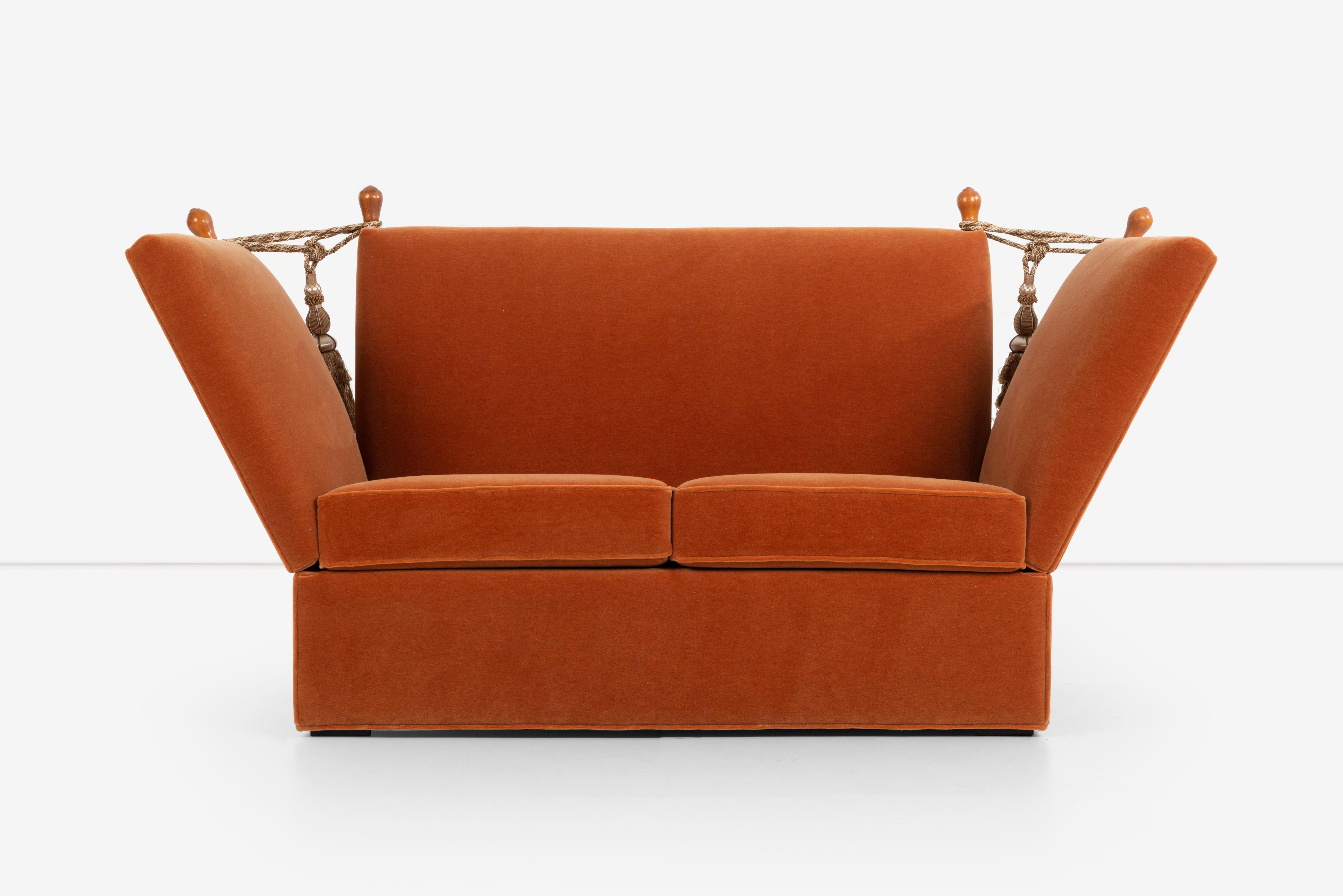 The Knole sofa is a classic English furniture piece that has been around since the 17th century. This particular Knole sofa, upholstered in burnt orange mohair, is a unique and stylish piece that is sure to make a statement in any room. The mohair