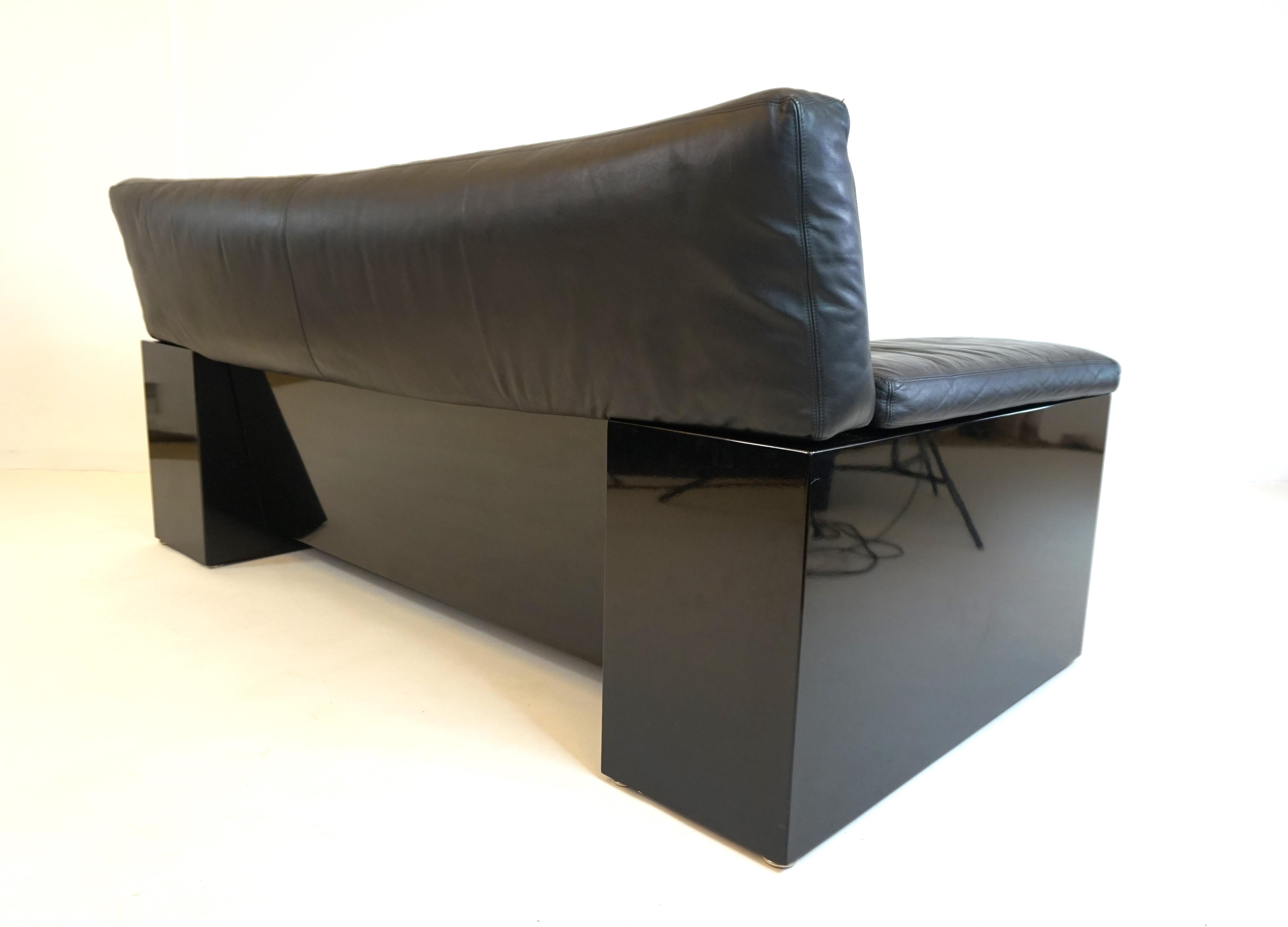 This Brigadier two-seater comes in excellent condition. The high-gloss painted black side cubes show no signs of wear. The soft, black leather is in very good condition. The suspension of the sofa is flawless and offers excellent seating comfort. A