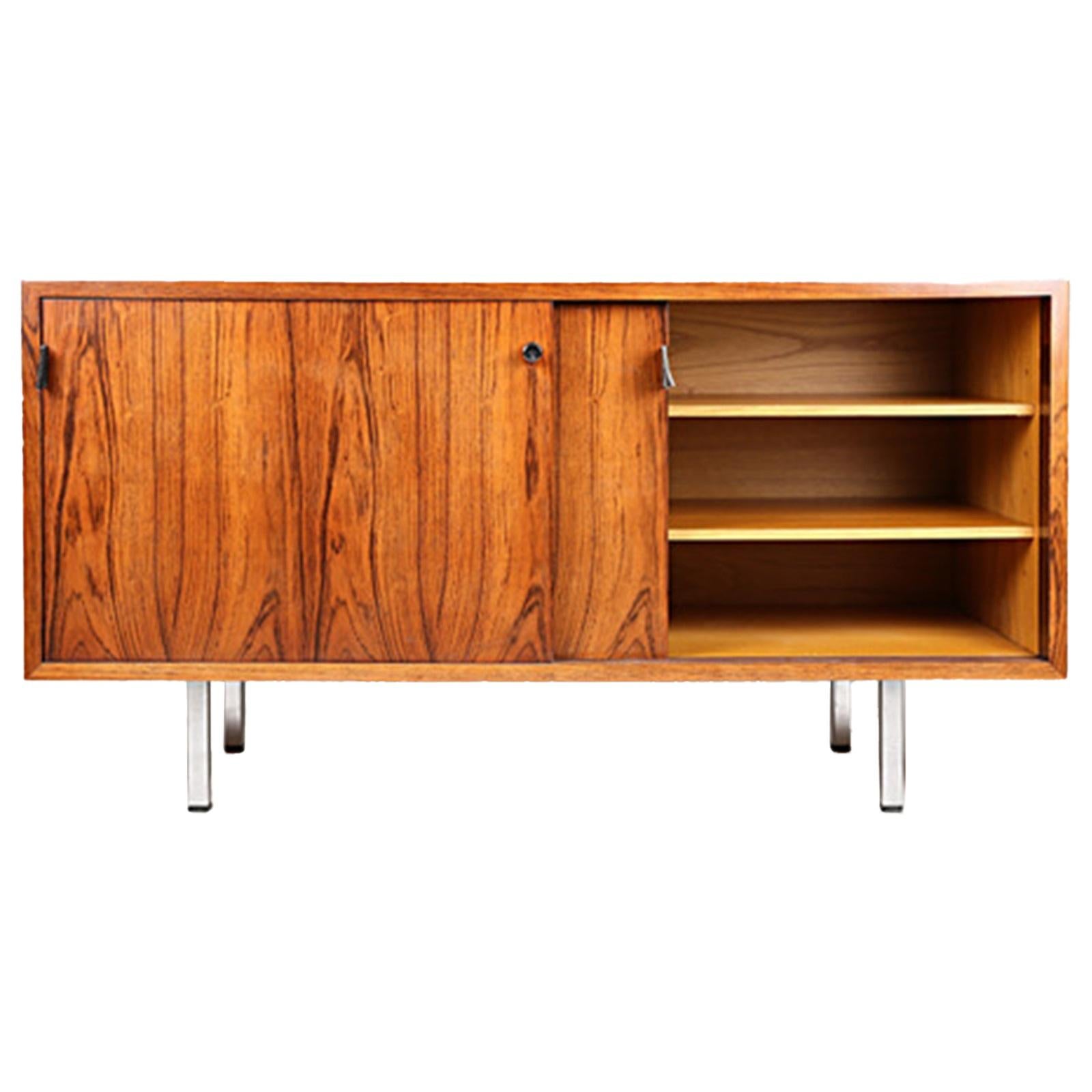 Knoll Florence (1917-2019) circa 1960
Office furniture in walnut and walnut veneer, it opens on the front with two leaves
sliding doors, leather pull straps, revealing two niches and four modular shelves.
It rests on four square section aluminum