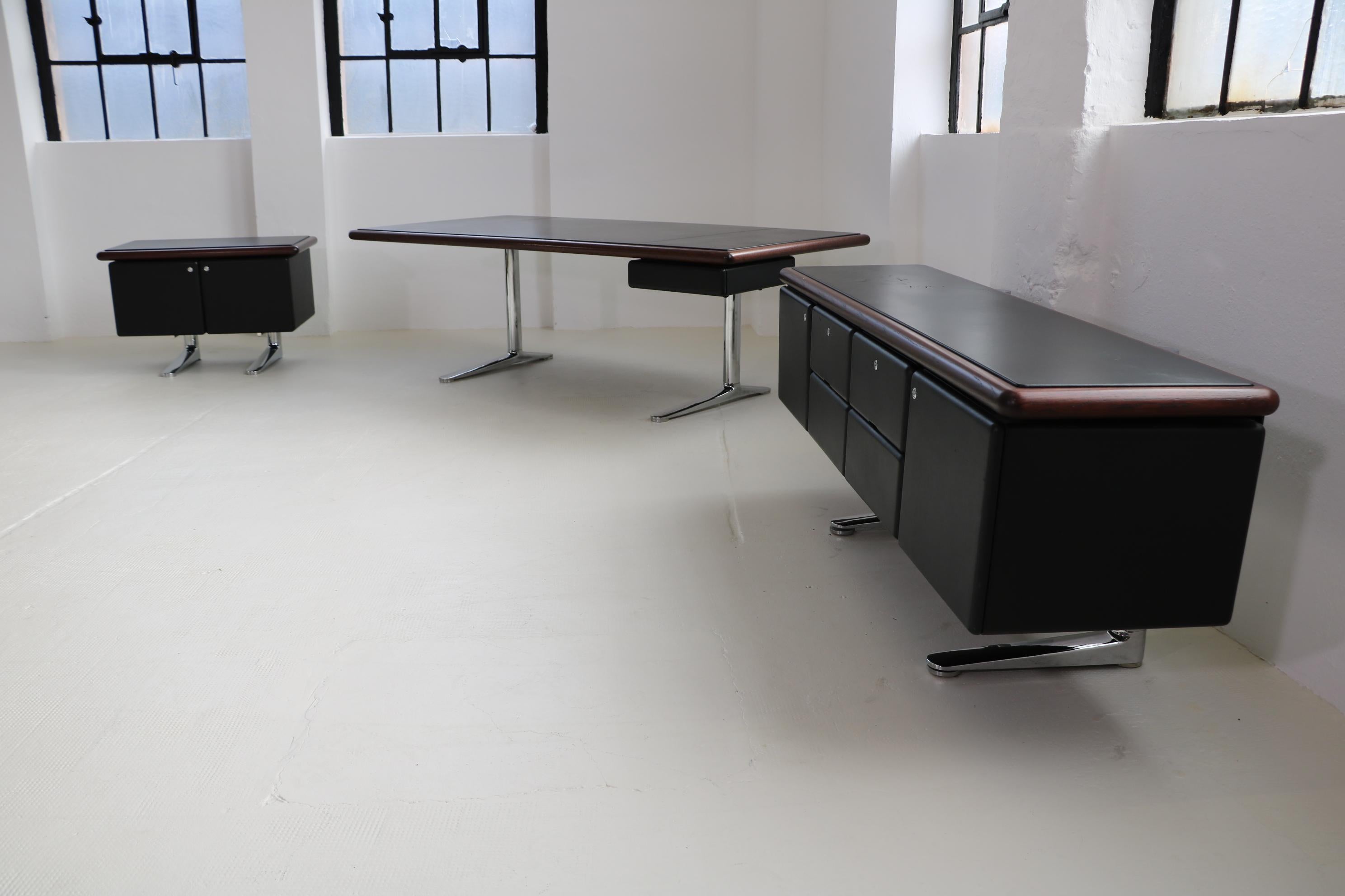Knoll International complete office by Warren Platner desk + sideboards

Desk: frame steel columns with special cast iron foot brackets chrome-plated, table top covered with black leather/edge solid oak, dark stained.
Dark stained, 1 x pull-out,