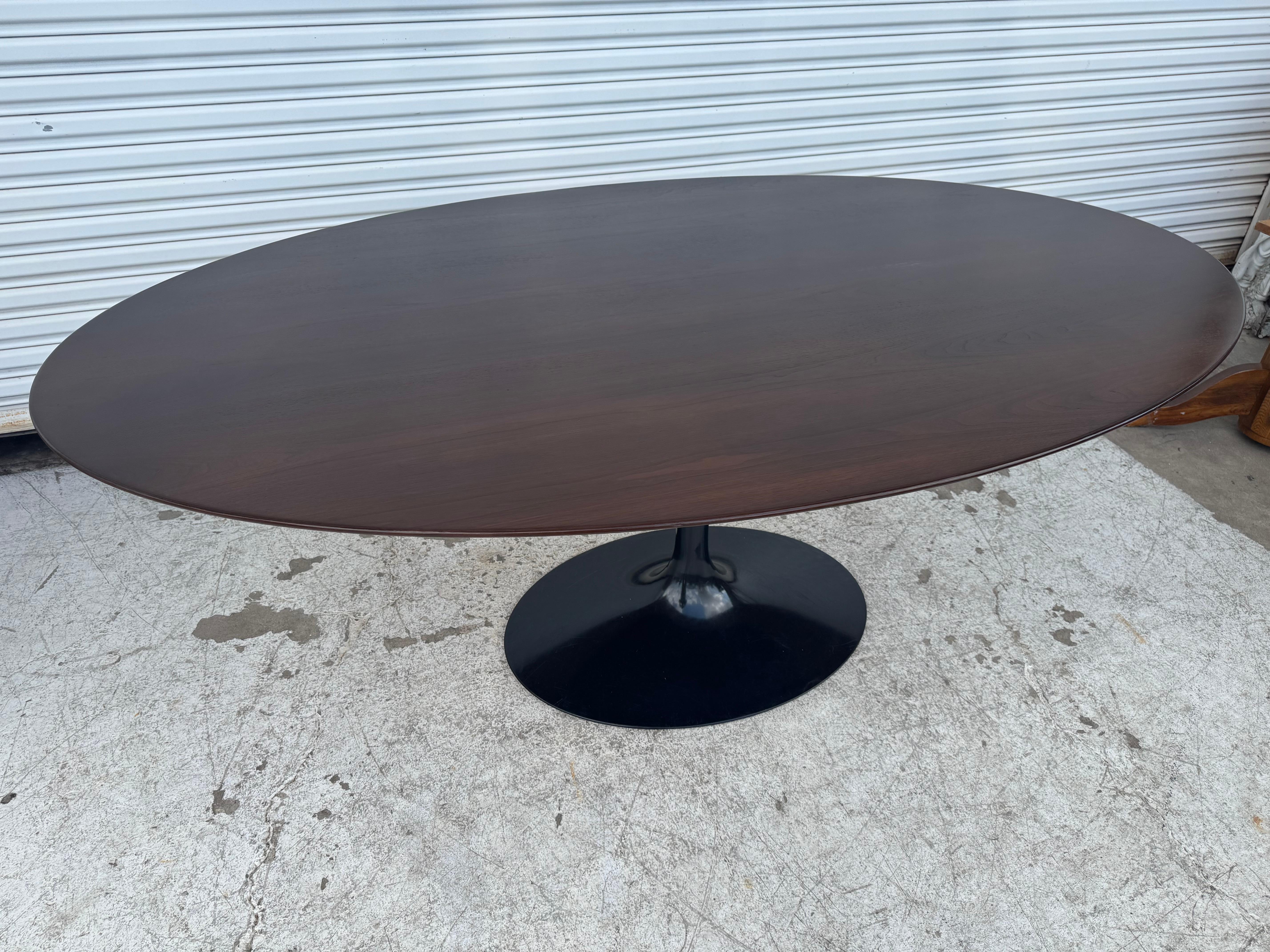 Il s'agit d'une table de salle à manger classique à base de Tulipe, conçue par Eero Saarinen pour Knoll Furniture.
La base est fabriquée en aluminium recouvert d'un revêtement en poudre émaillé noir.
La table est en noyer à grain supérieur et