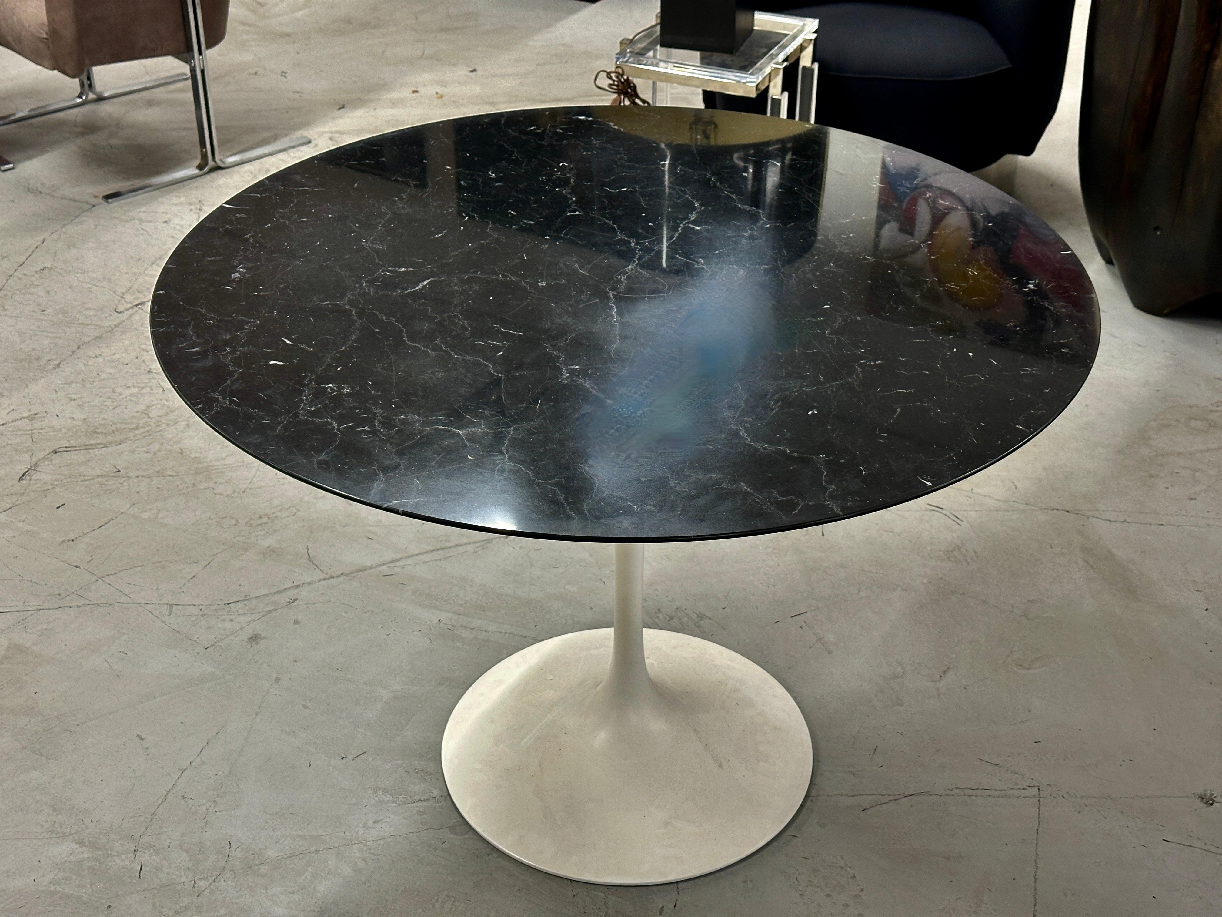 A lovely Knoll Tulip table designed by Eero Saarinen. It features a beautifully grained black marble top and white base. We acquired this table out of the estate of an antique dealer's home. It is 42 inches round and 28.5 inches tall. The top has