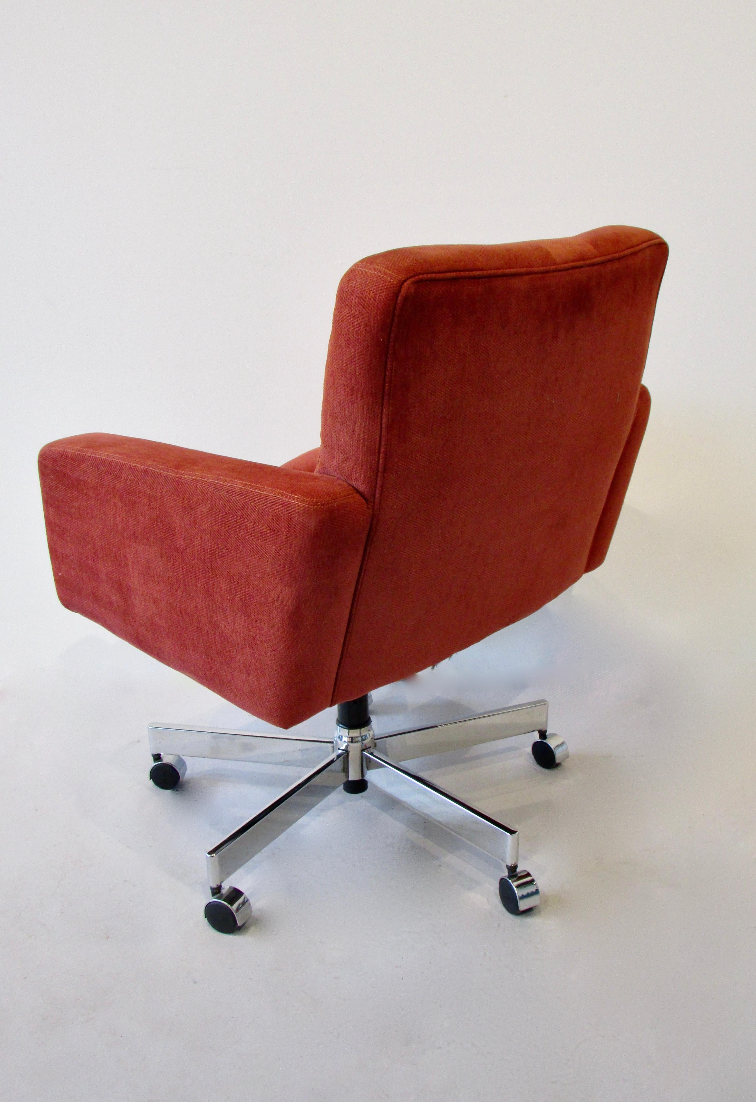 Swivel office desk chair in the style of Florence Knoll . Covered in rust tone fabric on five arm chrome base. Chair swivels and tilts. Minor discolorations from gentle use .