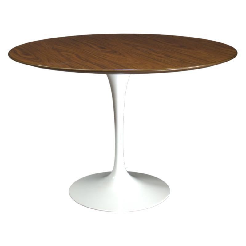 The Knoll Tulip Round Dining Table with Wood Top is an iconic design by Eero Saarinen. Known for its elegant and timeless design, this table features a sleek white pedestal base and a beautiful wood top, making it a perfect centerpiece for any