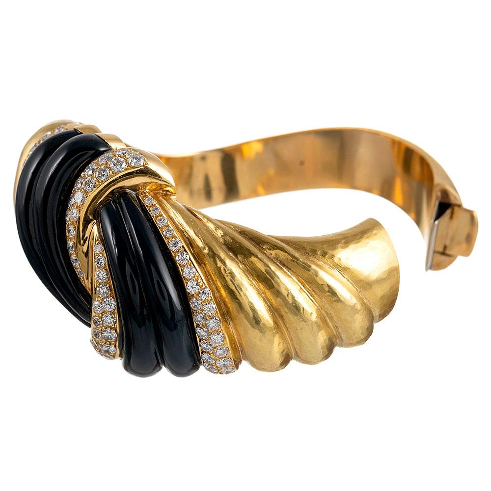 A substantial creation, rendered in 18 karat yellow gold with polished stokes of onyx knotted together with stripes of brilliant white diamonds. The stones weigh 3.86 carats in total. Note the subtly hammered texture of the gold… perhaps as a nod to