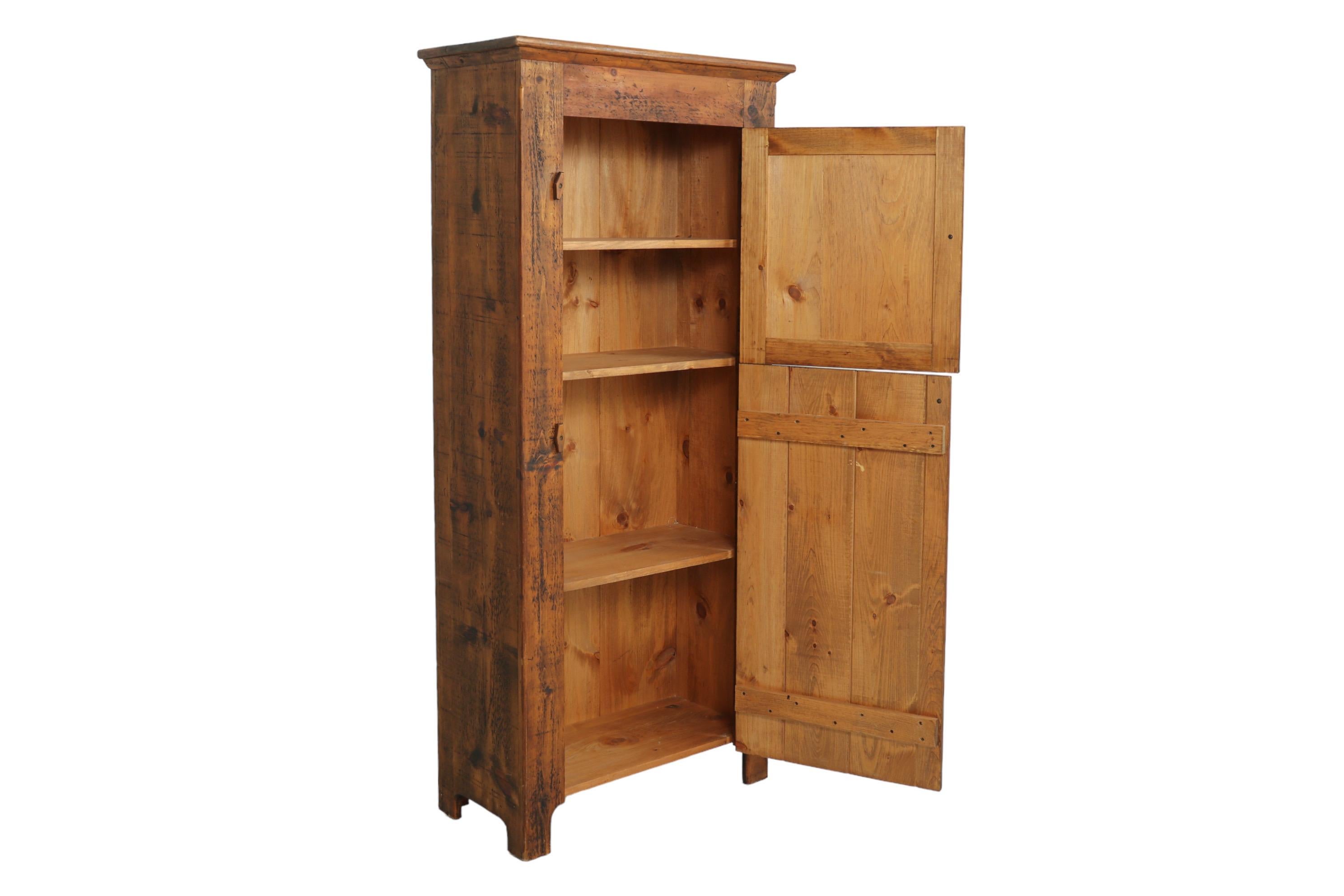 A farmhouse style hand painted cabinet made of knotty pine. Cabinet doors give the look of a Dutch door, with a cow's face painted on the upper cabinet door, and the lower door constructed of planks of wood. Doors open with mushroom knob handles and