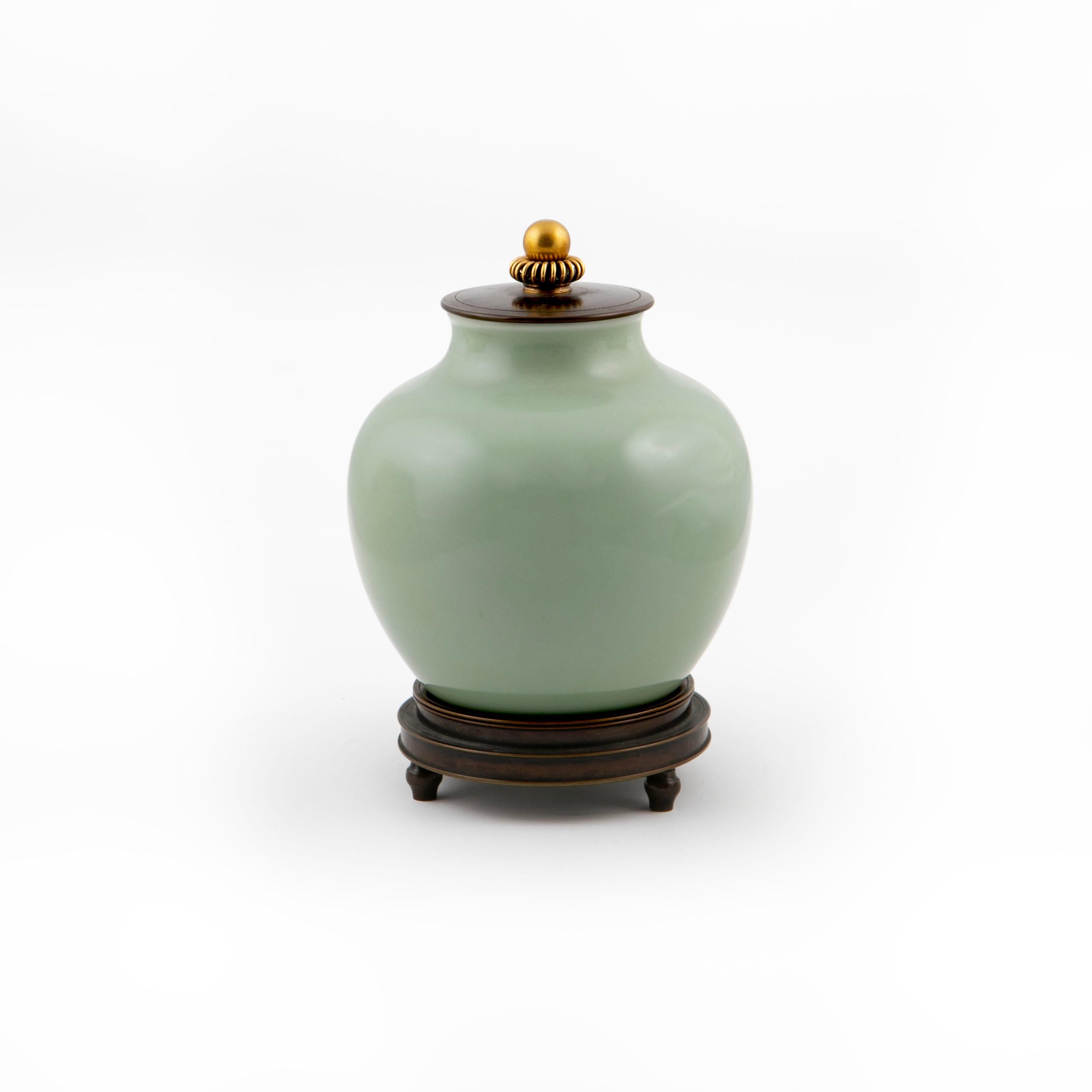 Knud Andersen (Danish, 1892-1966) for Royal Copenhagen.

Lidded stoneware vase decorated with green celadon glaze, fitted with patinated bronze lid and gilded knob. Resting on patinated bronze stand.

Produced and stamped 1/3336 in Royal Copenhagen.