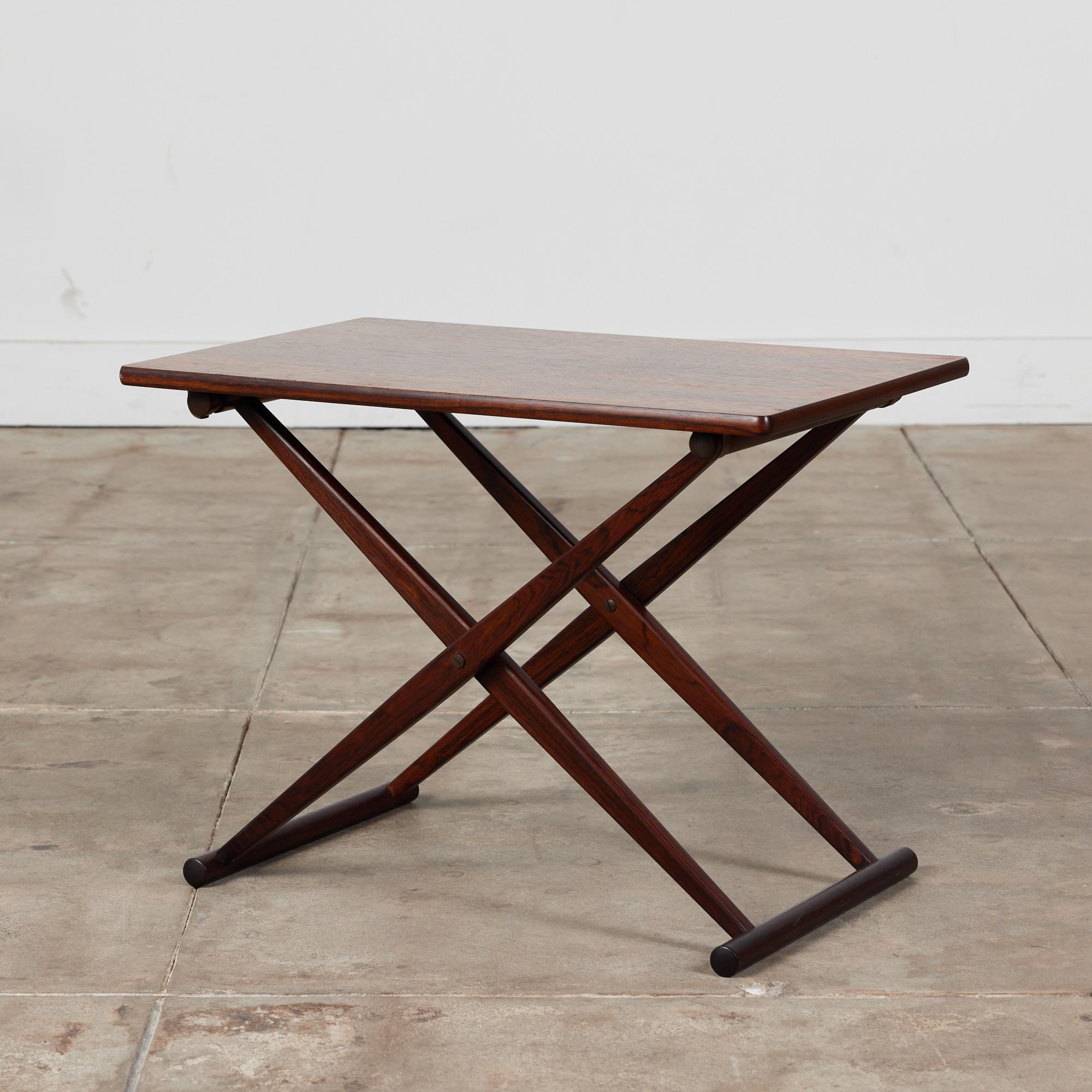 Danish rosewood side table by Knud Andersen c.1950s for Aarhus. The rectangular folding table features a rich wood grain on the table top and an x-folding base with dowl feet. A simplistic yet timeless design.

