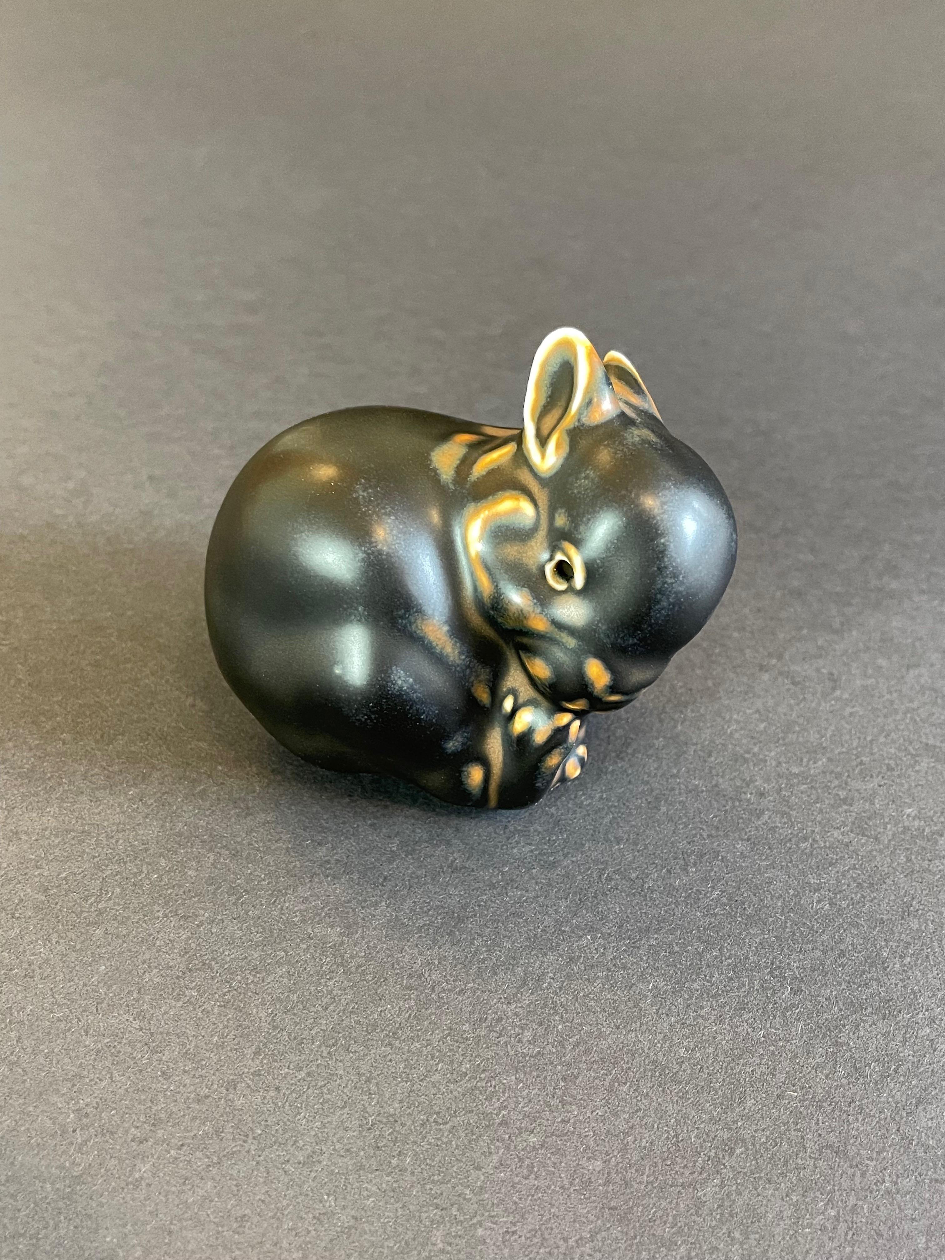 Assolutamente adorabile ed elegante statuetta di coniglio in porcellana danese di metà secolo realizzata dal famoso artista Knud Kyhn (danese, 1880-1969) e risalente al periodo 1965-1975 circa. 
Il coniglietto è realizzato con il tipico smalto opaco