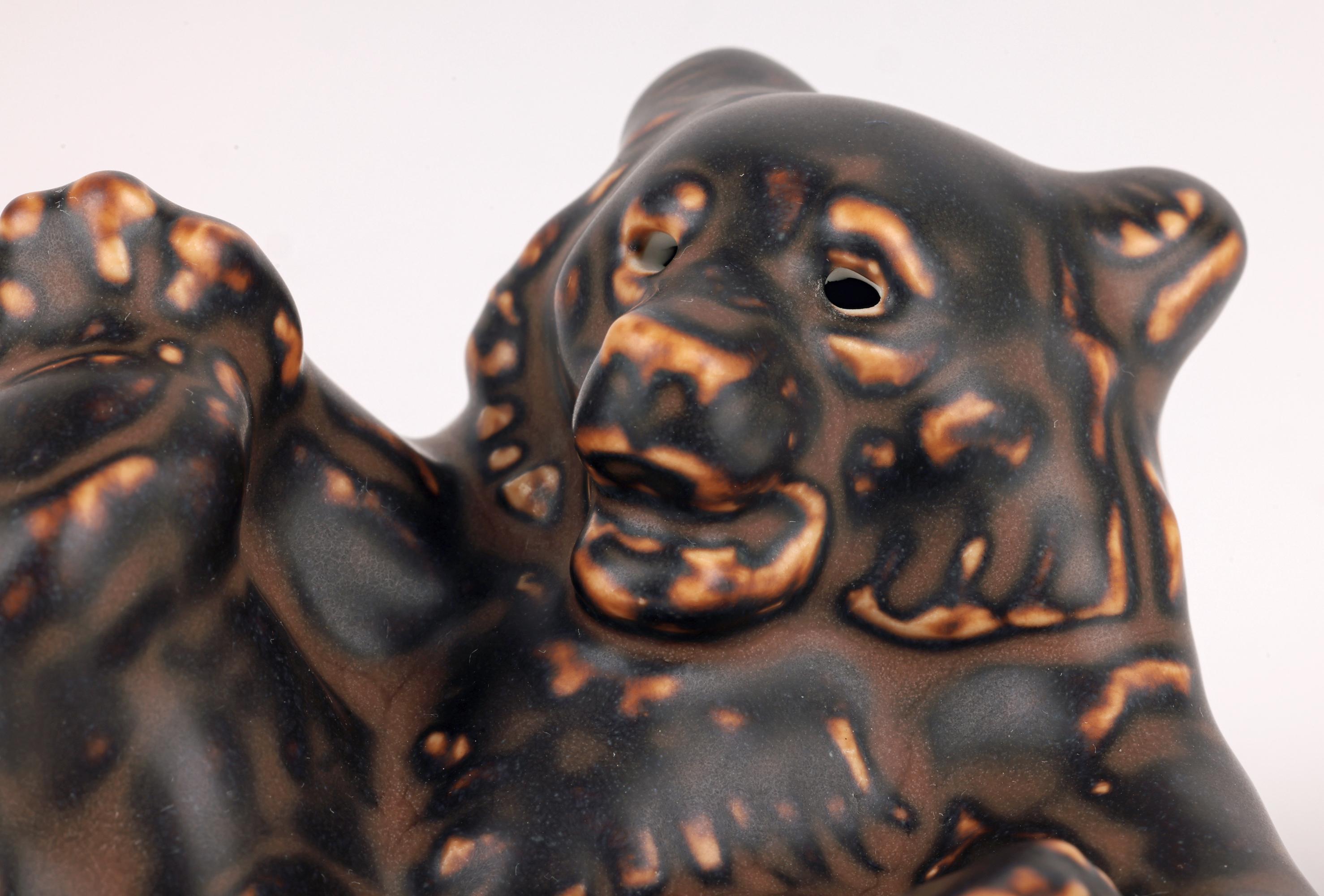 A delightful and stylish mid-century Danish Royal Copenhagen porcelain lying bear figure by renowned artist Knud Kyhn (Danish, 1880-1969) and dating from around 1950. The lying bear is modelled lying on its back with its paws raised and playing with