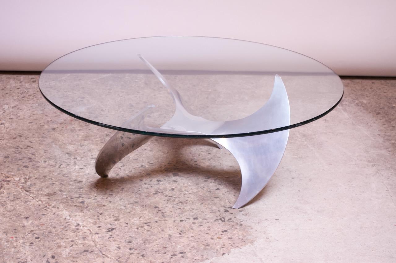 1960s German coffee table by Knut Hesterberg for Ronald Schmitt featuring a sculptural polished aluminum propeller-form base with a glass top. 
 Iconic, statement piece in original condition with light wear consistent with age / use (a few light