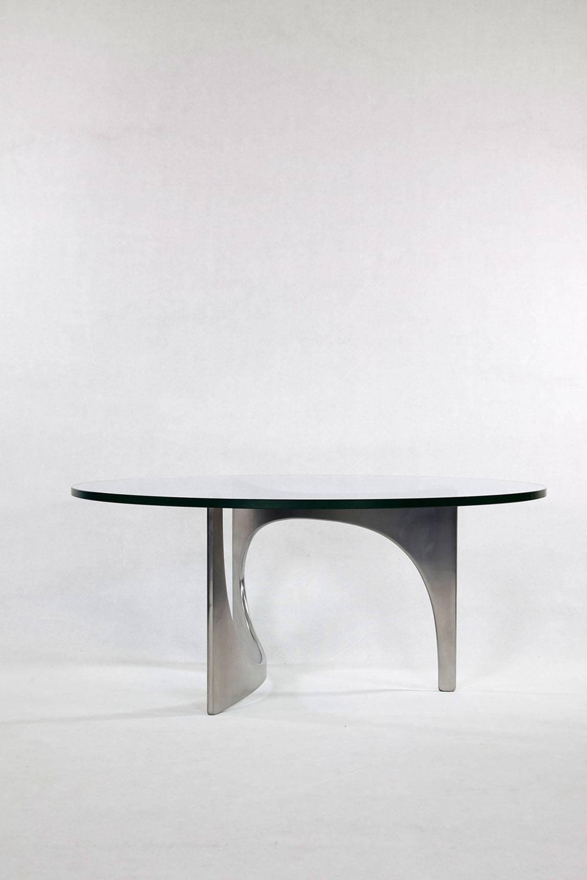 This coffee table was designed by Knut Hesterberg and manufactured by Bacher-Tische in Stuttgart in the 1960s. The unusually shaped base is made of polished aluminium, the round top made of crystal glass only rests loosely due to its weight. This