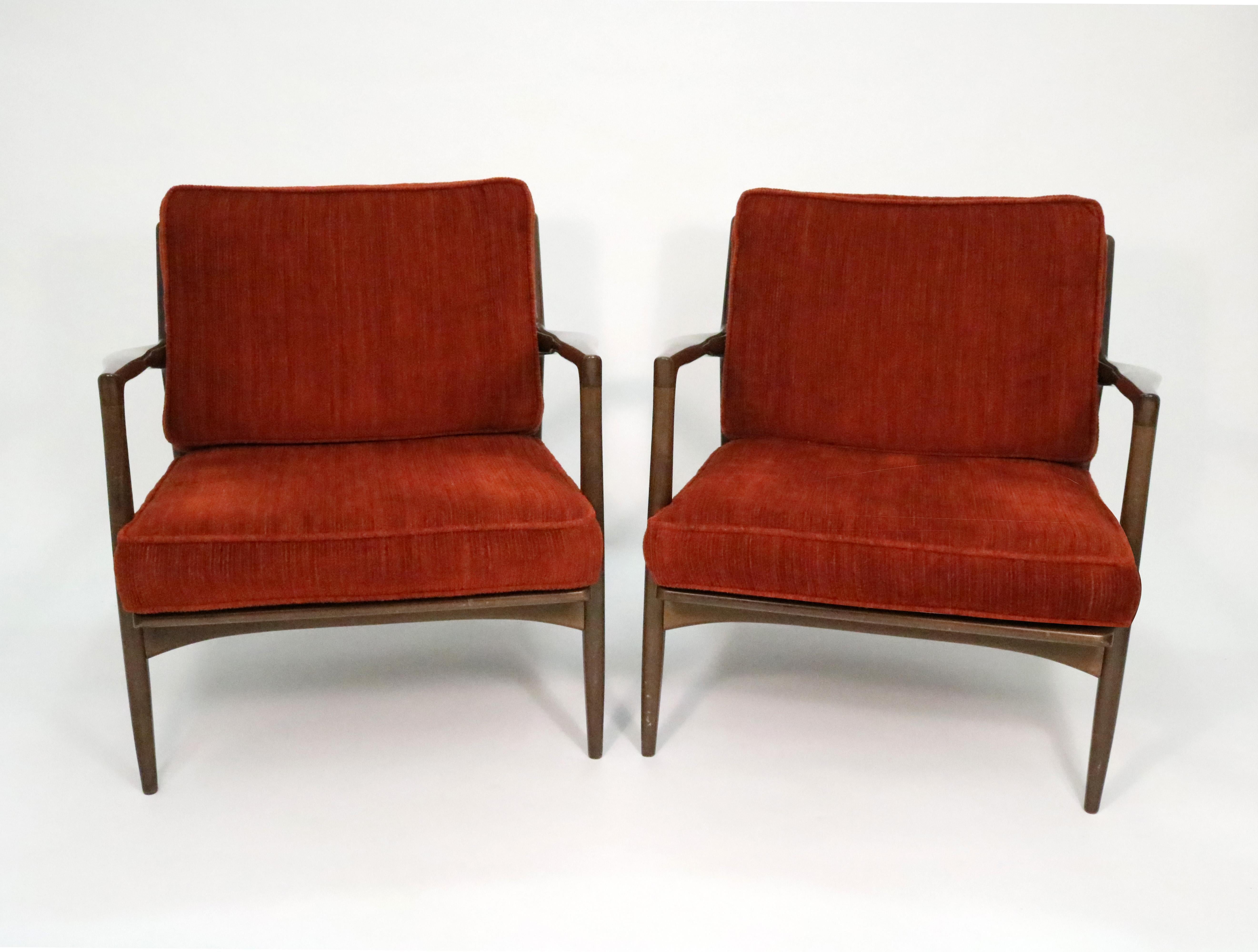 A pair of elegantly sculpted Danish Modern lounge chairs by Ib Kofod-Larsen for Selig in dark walnut.