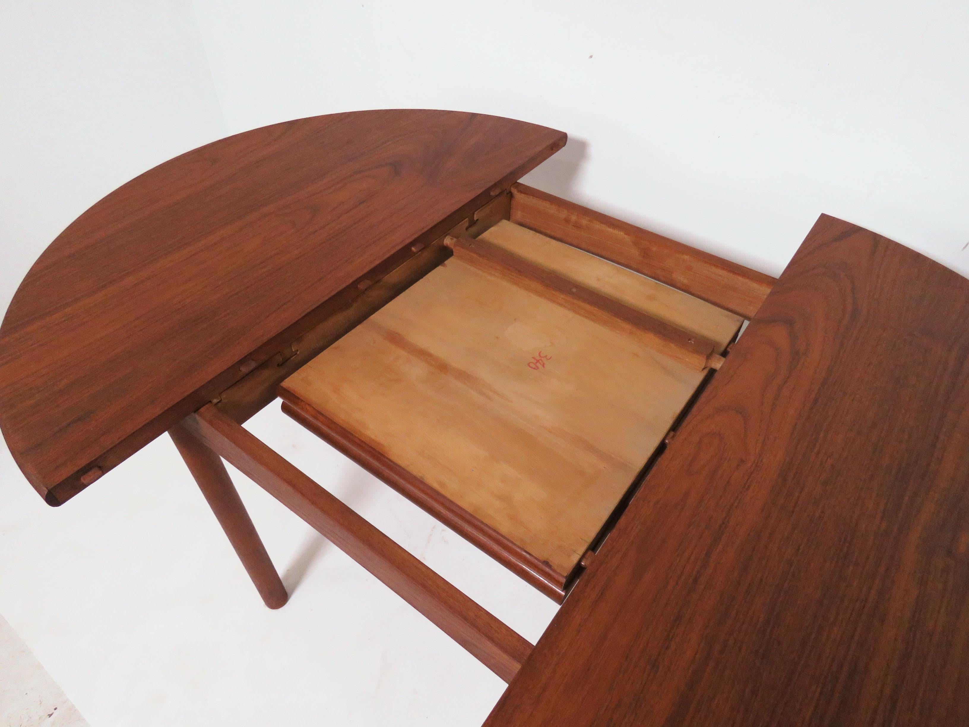 Danish dining table with hidden butterfly leaf, by Ib Kofod-Larsen for Christensen & Larsen, circa early 1960s. He created this rare model with a top of highly figured padouk wood (which exhibits a grain pattern akin to rosewood with the color of