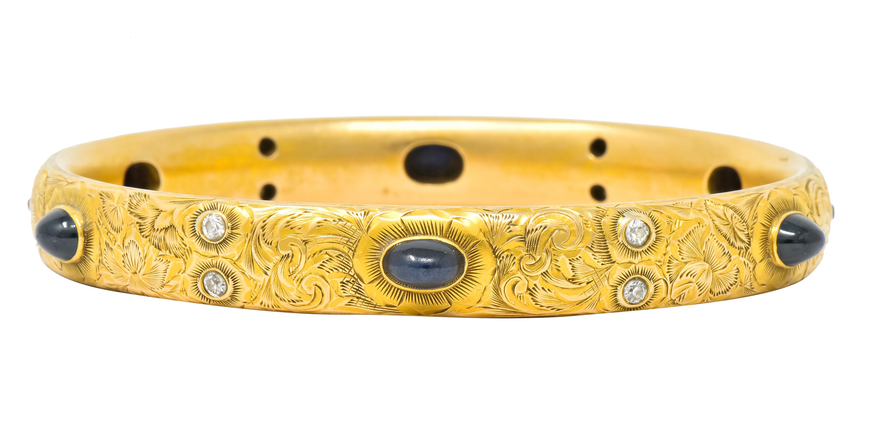 Hollow bangle bracelet fully hand engraved with floral and foliate motif

With sapphire bullet cabochon stations measuring approximately 7.0 mm, dark inky blue/green in color

Accented by bezel set old European cut diamonds weighing approximately