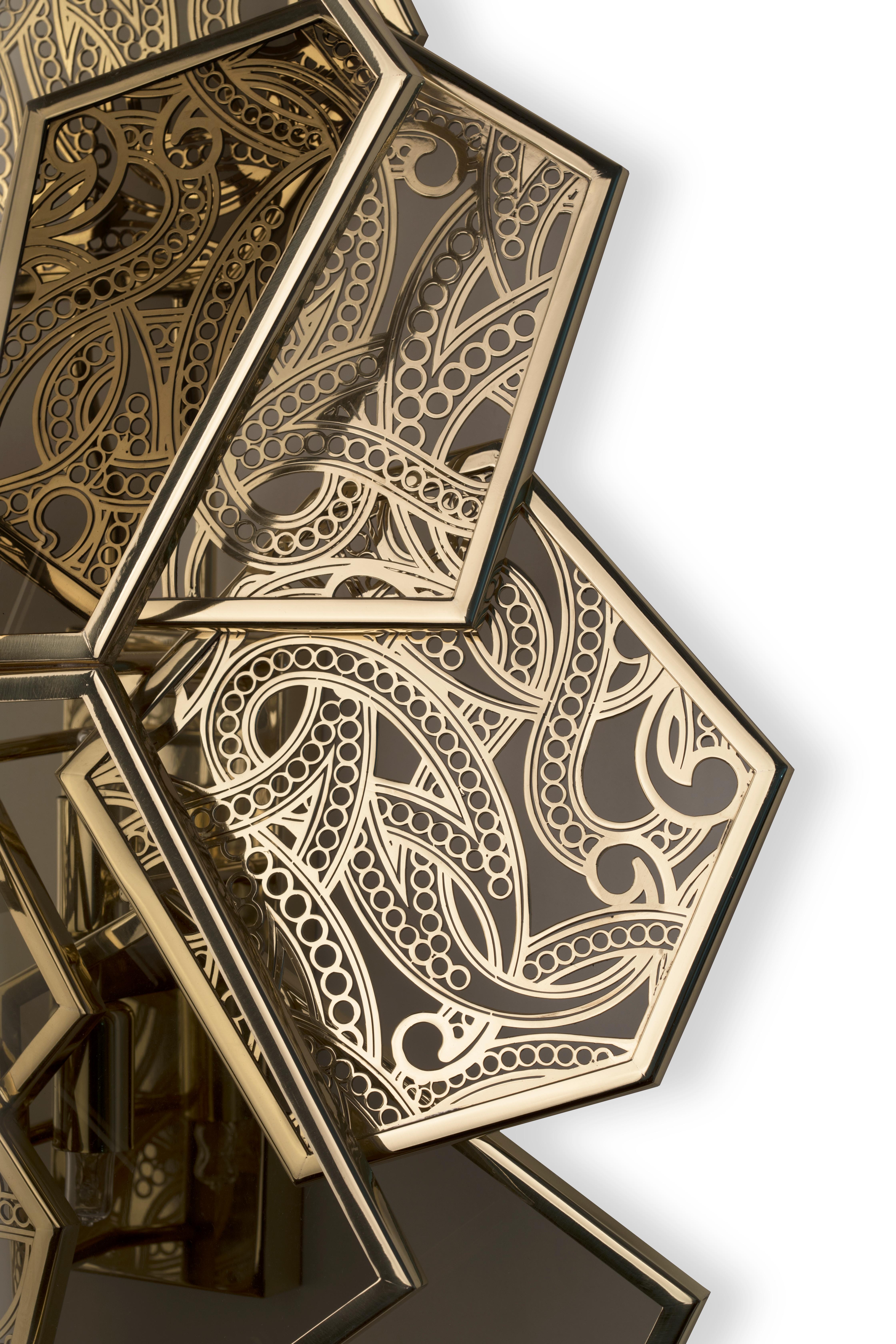 This sleek and elegant sconce will hypnotize its audience. You will become mesmerized as the intricately fashioned sconce coils and bends in golden spirals; weaving itself elaborately within the sharp polished lines of the hexagonal silhouette. The