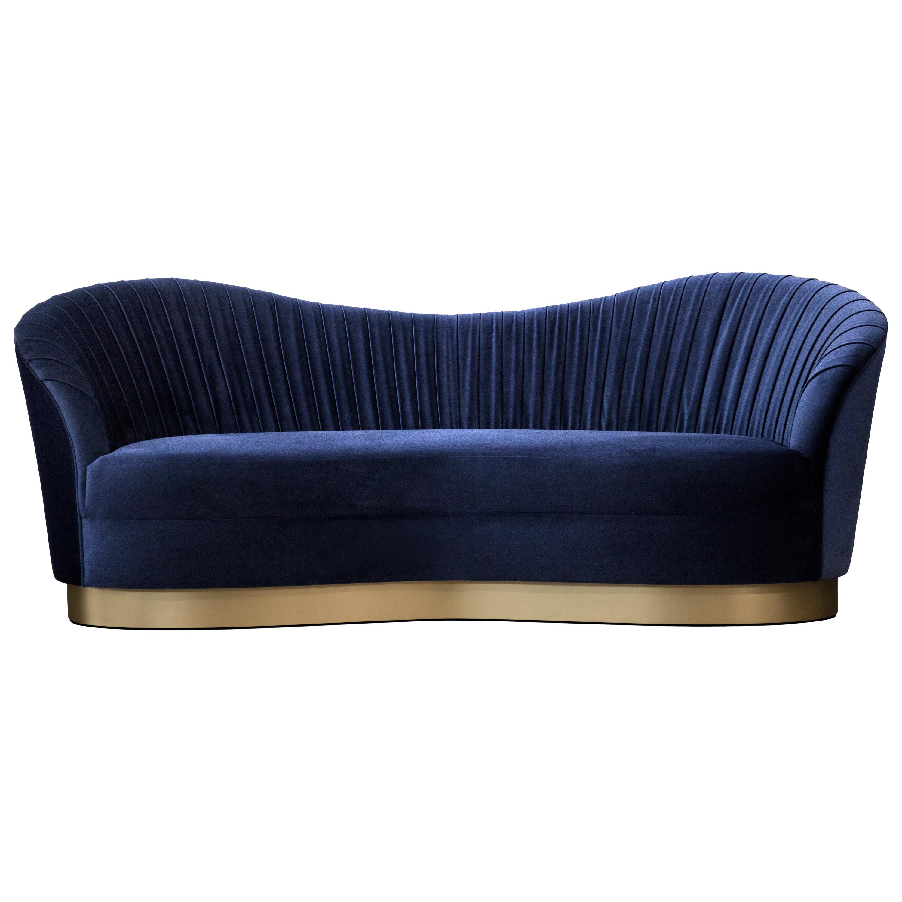 The lux and bodacious Kelly sofa is the cool girl sipping Cosmos in the dark corner of a chic NYC lounge. Her fluid curves are harmoniously matched by sumptuous pleated waves of soft upholstery fabric. Her tell is a striking metal band hugging the