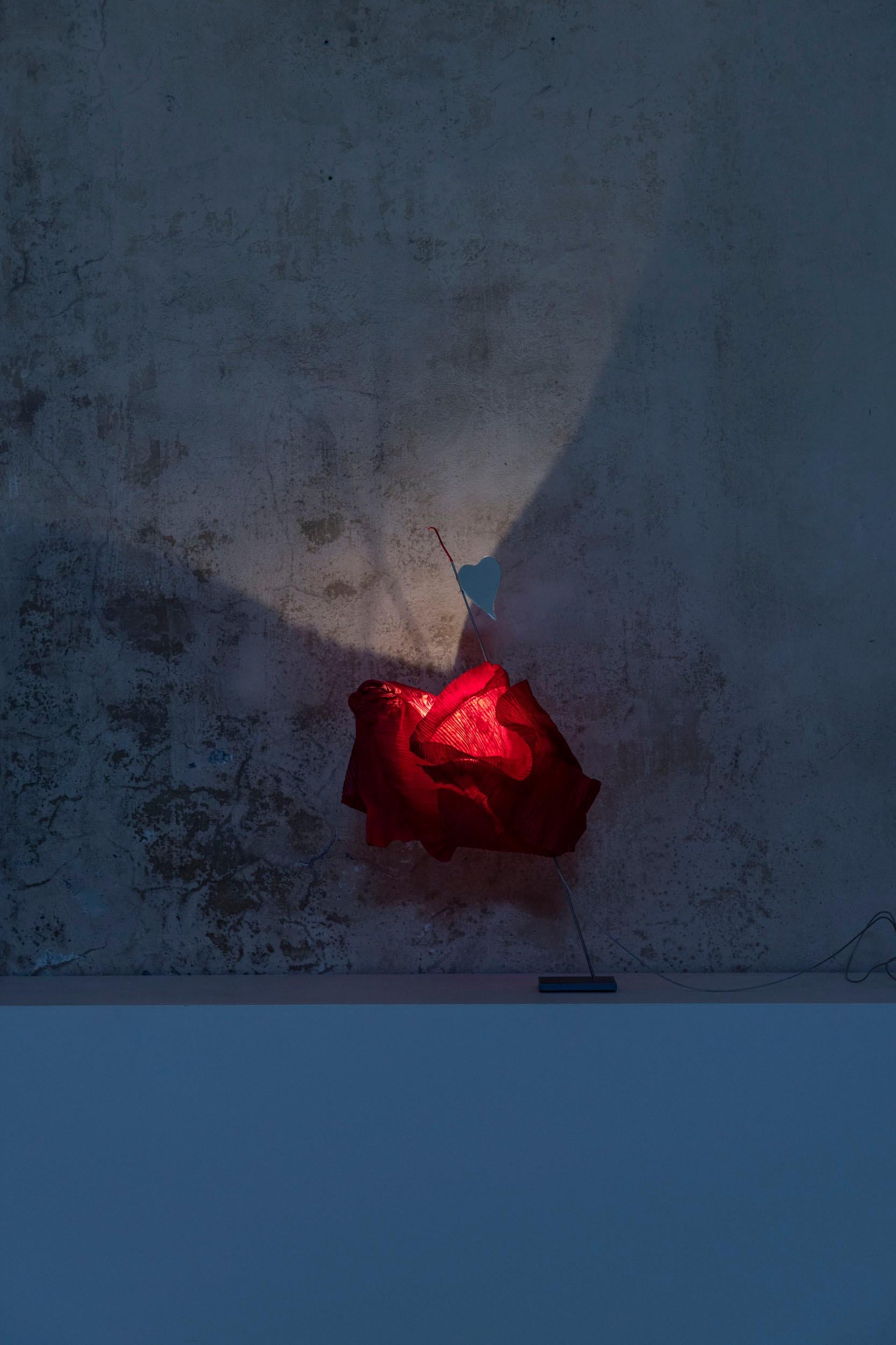 Kokoro d'Ingo Maurer est une lampe sculpturale captivante. Elle comporte un miroir en forme de cœur placé au-dessus d'un abat-jour en papier rouge aux formes complexes. 
Les abat-jour en papier fait main, fabriqués à Munich, utilisent du papier