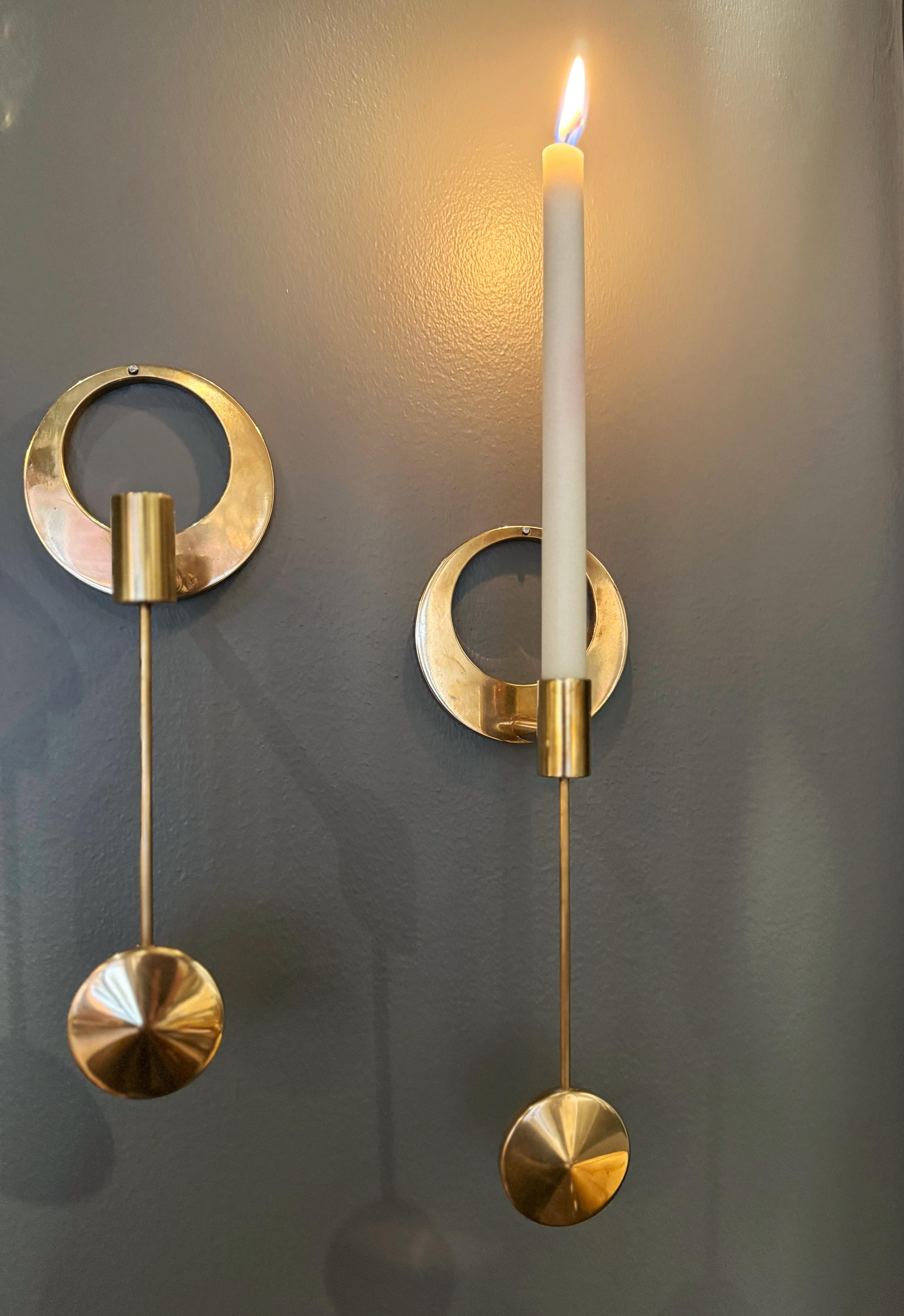Satz von 2 Wandkerzenhaltern aus Messing von Arthur Pe Pettersson Kolbäck, Schweden.
Modernistische Kerzenständer aus massivem Messing, hergestellt in den 1960er Jahren.  
Runder Wandsockel mit einer in einem Pendel befestigten Fassung. 
Zur