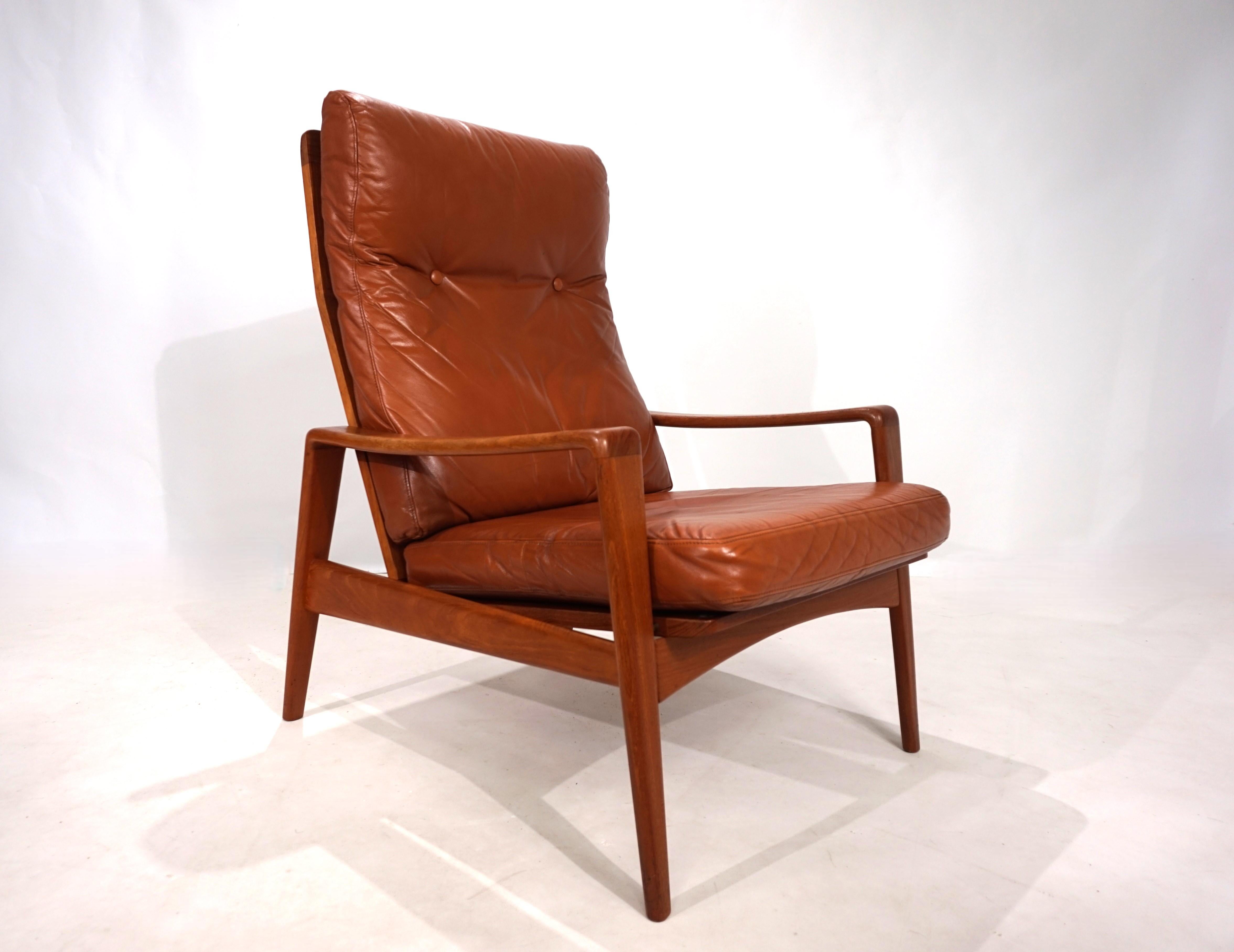 Questa poltrona di Arne Wahl Iversen colpisce per le sue forme organiche, che si adattano a qualsiasi ambiente. La delicata cornice in teak di una tonalità calda è in ottime condizioni. La pelle color caramello presenta una patina leggera e