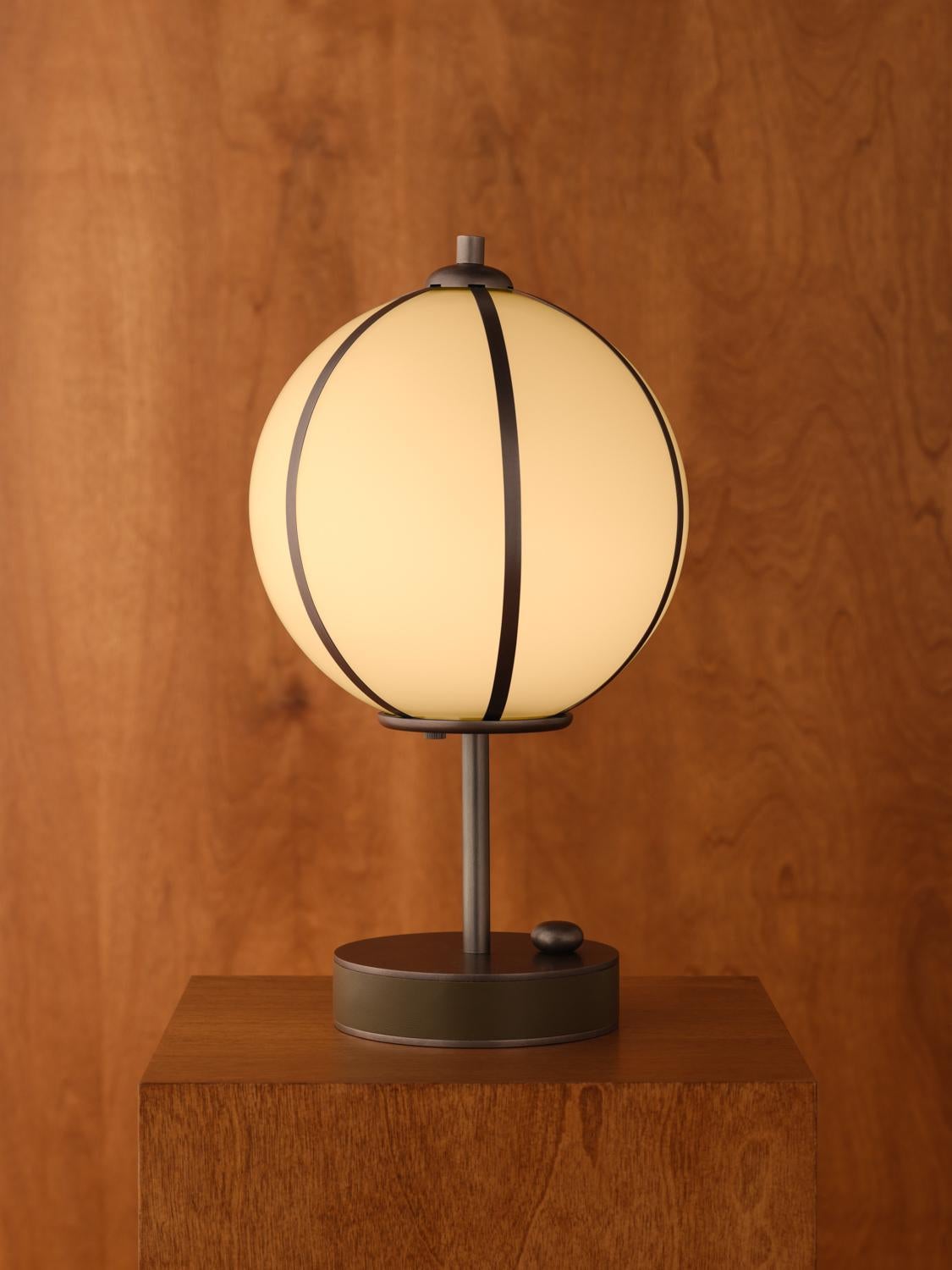 The Rib Table Lamp Ellipse features glass blown in Italy and delicately framed by thin brass ribs. A cylindrical brass base is wrapped in leather or suede, enhancing the rich interplay of colors and textures.

The Rib Table Lamp is available in a
