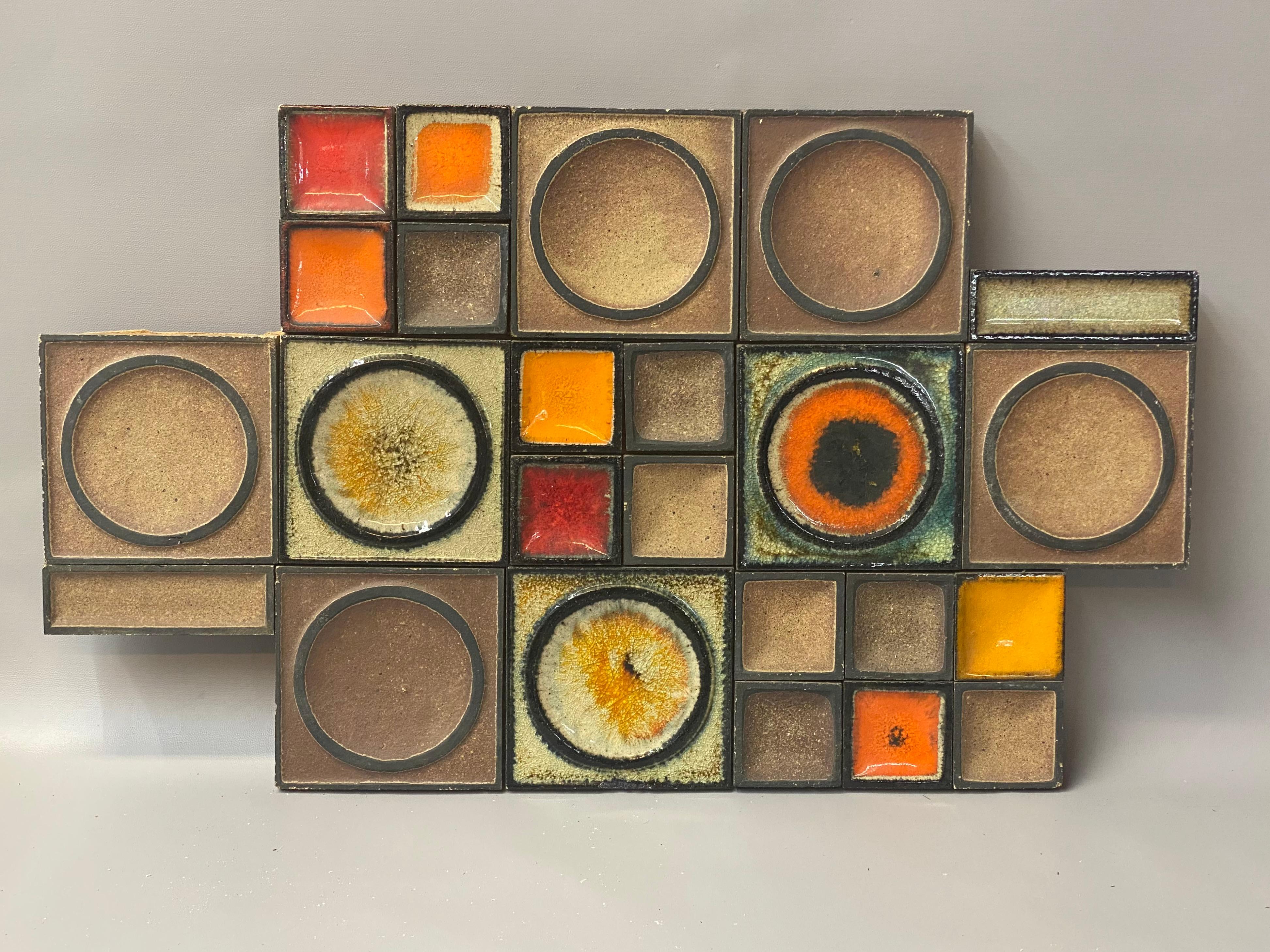 A beautiful pottery tile wall hanging by the studio of Konrad Galaaen, Norway. Geometric fired tiles contrasting in finish from a matte to glossy glazes. Twenty four tiles in total. The smaller square tiles pop with highly saturated orange and red