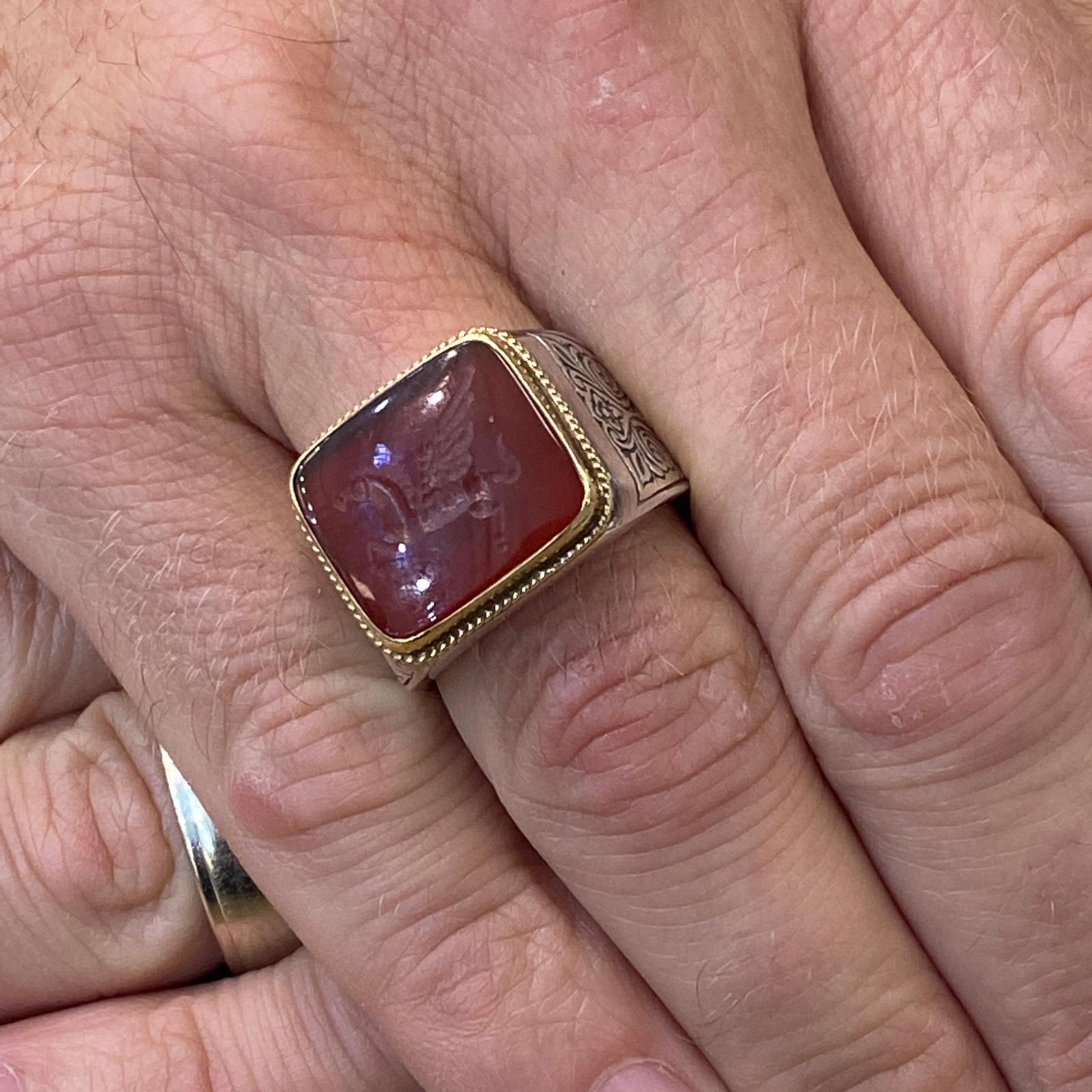Men's carnelian ring by Konstantino fashioned in sterling silver and 18 karat yellow gold. The carnelian intaglio is bezel set in yellow gold and measures 15mm in width. The ring is currently size 9 (can be sized). 