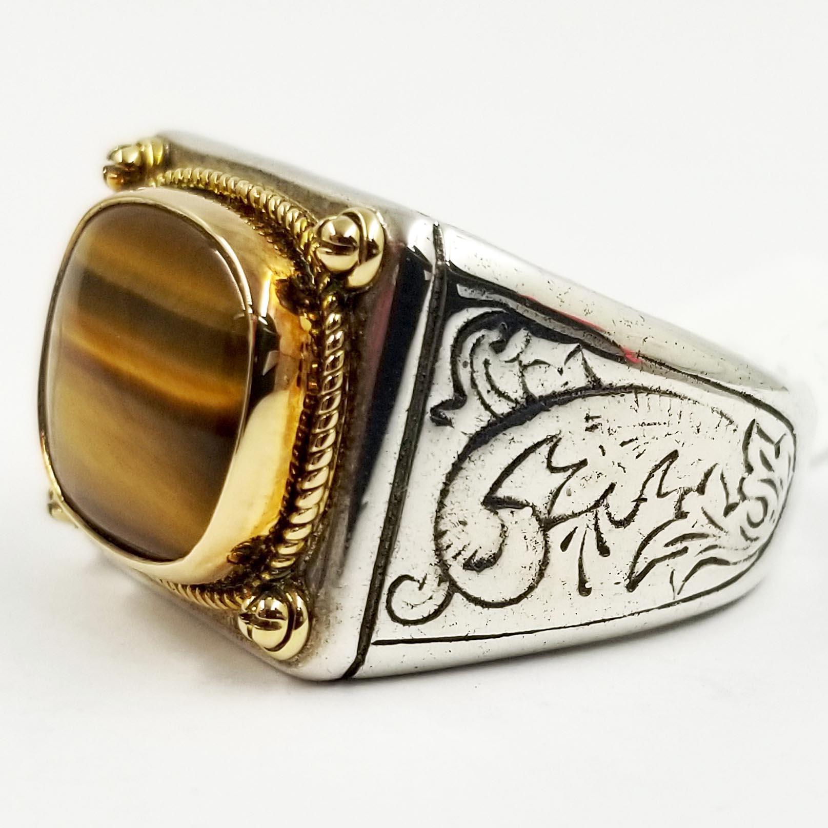 Sterling silver Konstantino ring featuring 18 karat yellow gold bezel set tiger's eye center and floral engraved motif throughout shank.
Metal Type: 18K Yellow Gold, Sterling Silver
Hallmark: 750, 925, Brand Hallmark
Location: Inside Shank
Metal