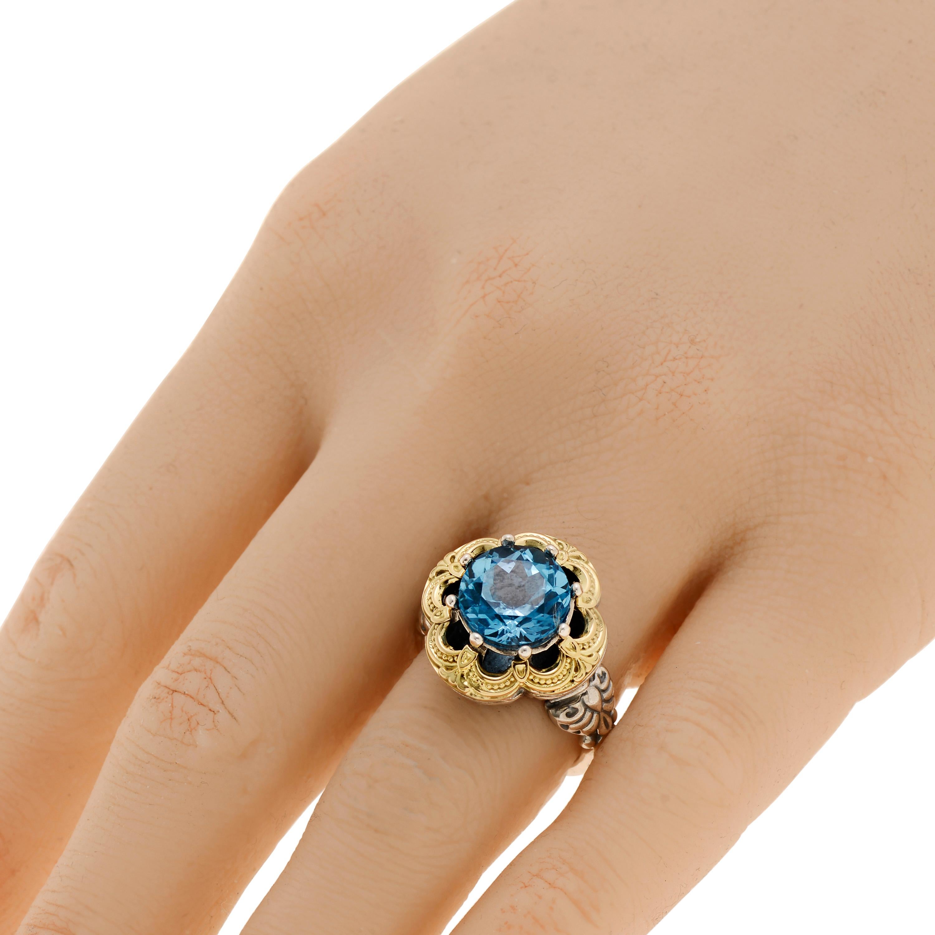 This beautiful Konstantino ring features blue topaz set in sterling silver with 18K yellow gold accents. The decoration size is 3/4”. The weight is 11g. The ring size is 7 (54.4).
