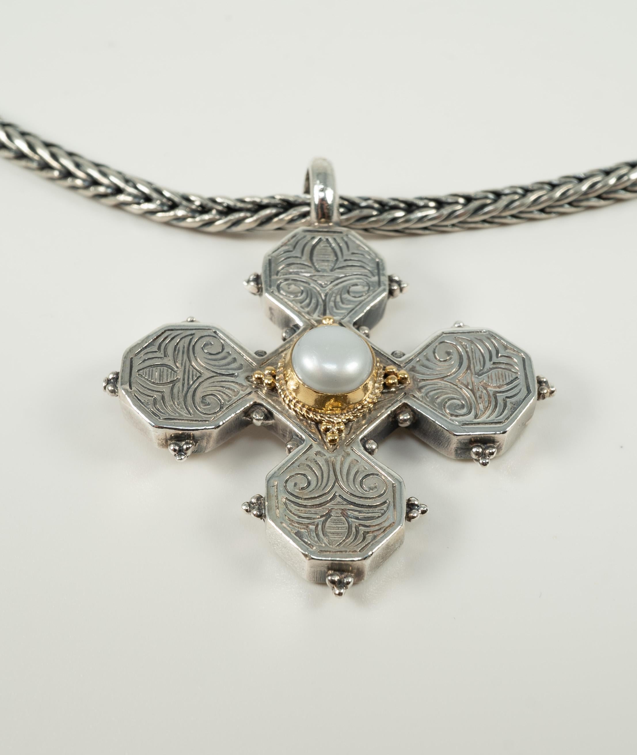 Composed of a 17 inch sterling silver chain, suspending a sterling silver, yellow gold and pearl cross pendant.  The pendant measures 1.85