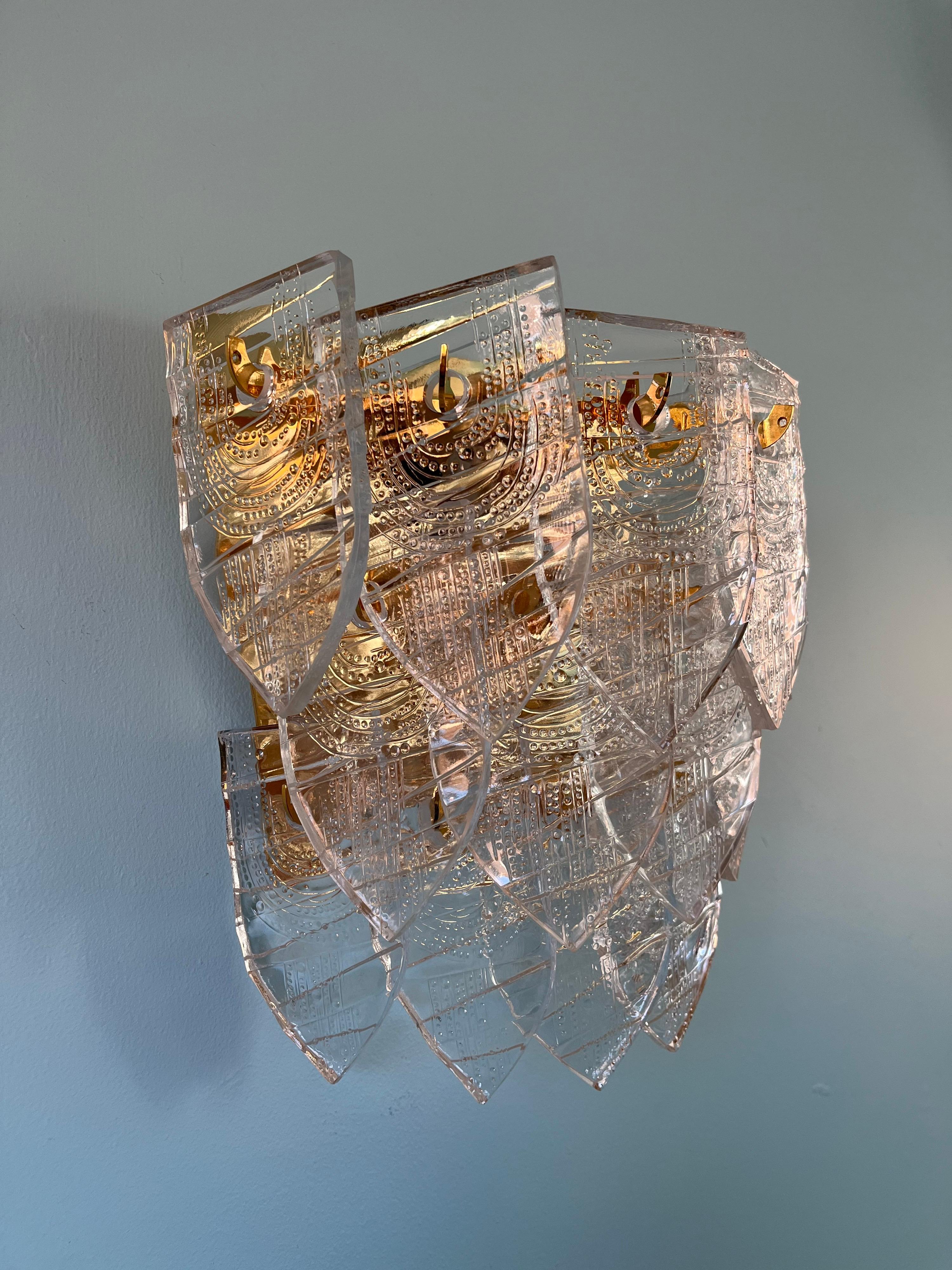 Gunnar Cyren for Orrefors, single gold plated frame holding 17 thick pressed crystal pieces divided on three rows lid up by 3 candelabra bulbs.
The individual pressed crystal pieces has small pattern to them, they were produced by melting crystal