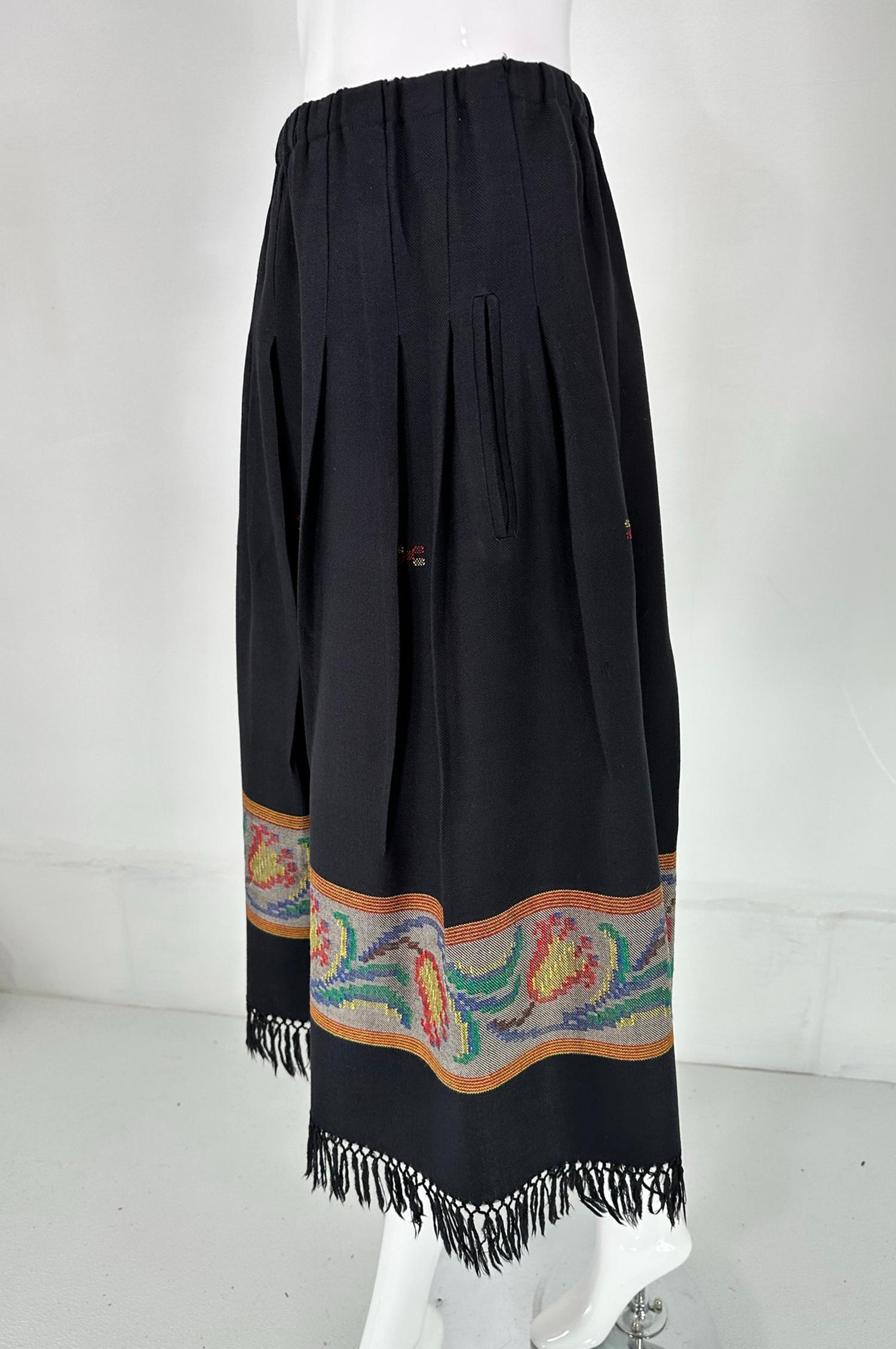 Koos van den Akker hand woven fringe hem, pleated skirt from the 1980s. Mid weight wool twill with a woven border hem and hand knotted fringe hem. Hip front vertical besom pockets. Pull on with a cased elastic waist band. Unlined. 
 In excellent