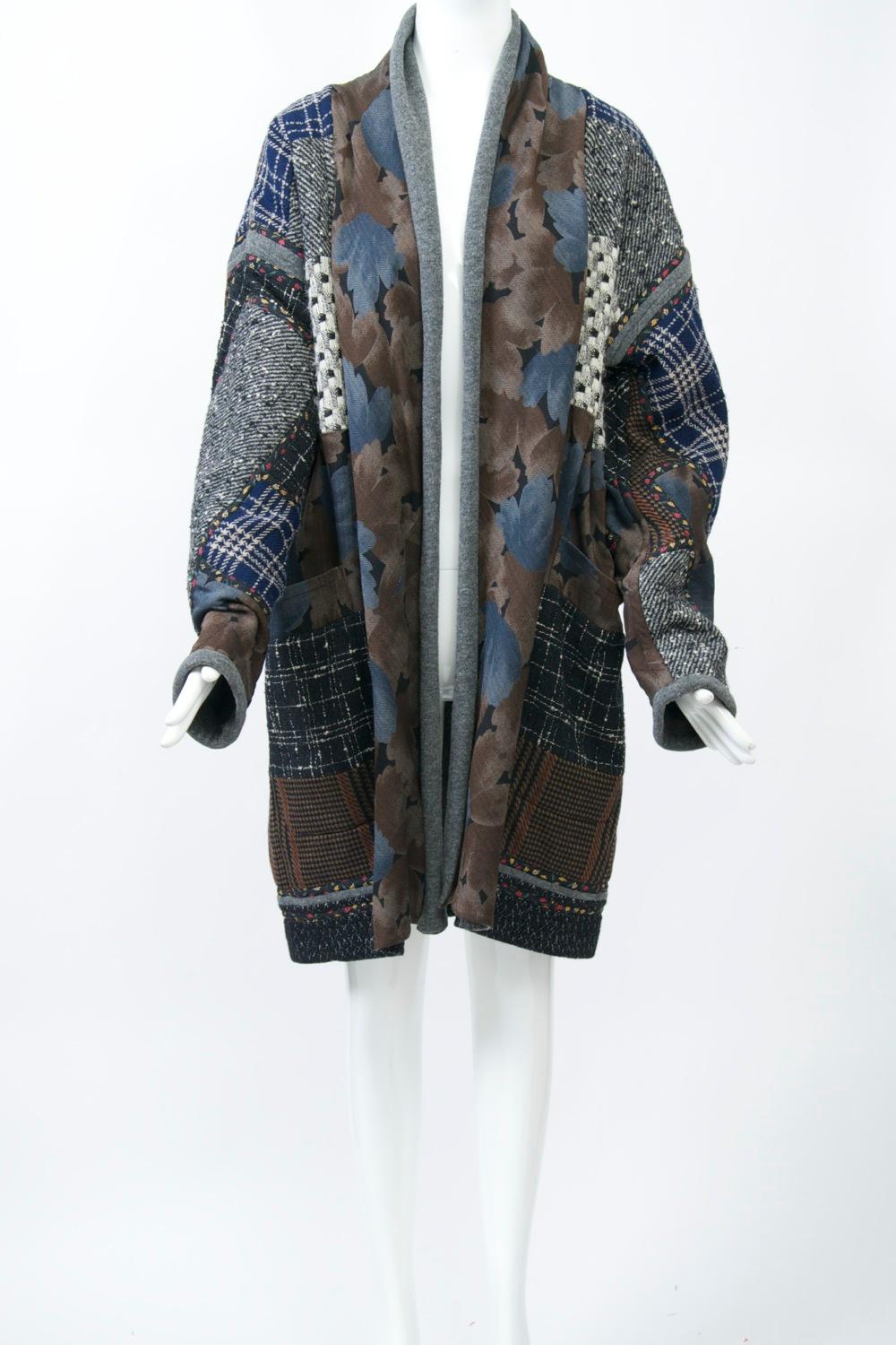 1980s Koos van den Akker jacket in iconic patchwork design. Crafted of patterns in predominantly grays, taupes, and dark blues. Loose fitting 1980s style with dropped shoulders and open front. Lined in gray wool knit.