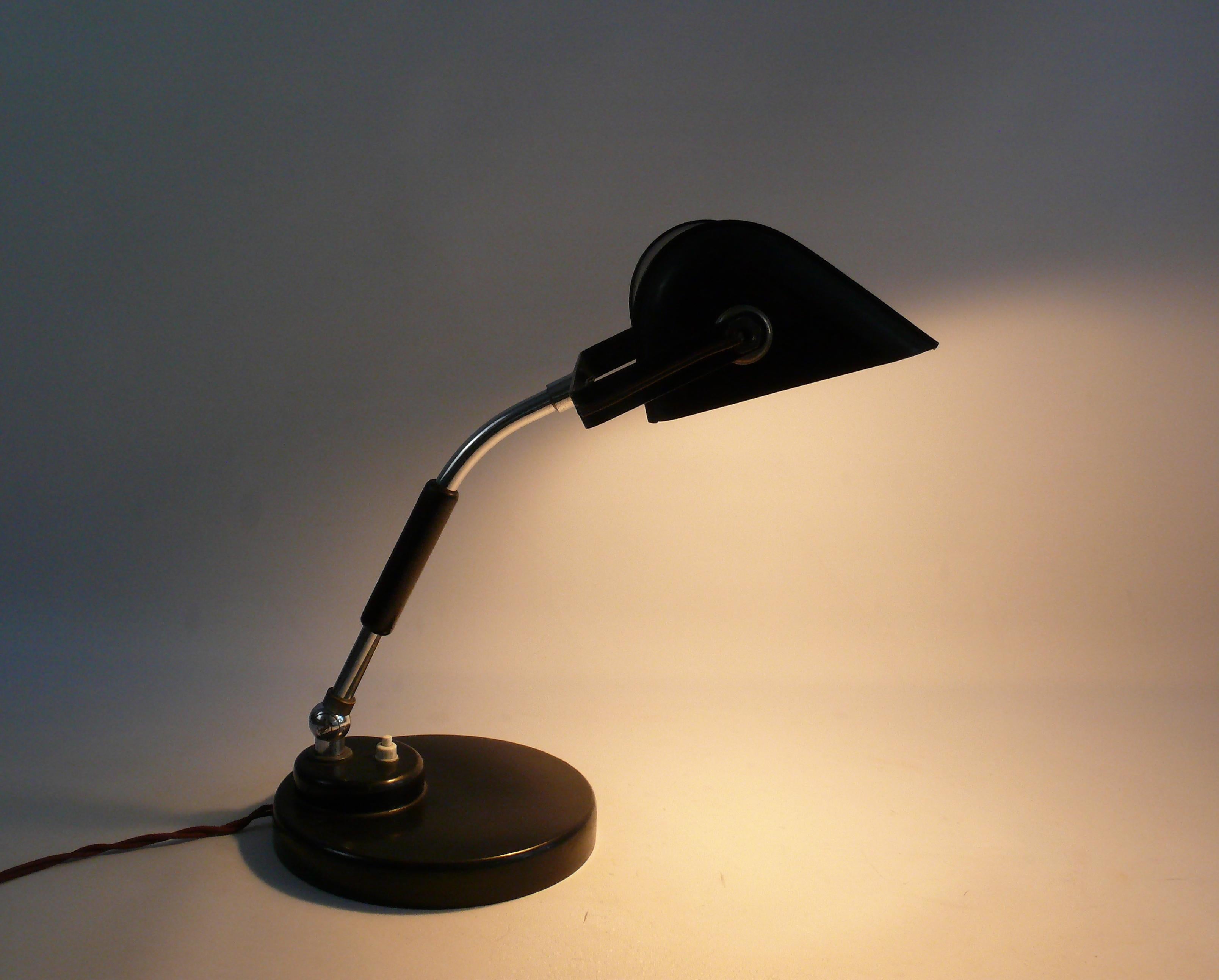 Gut erhaltene Bankerlampe/Tischlampe aus den 1930er Jahren im Bauhaus-Stil. Hersteller wahrscheinlich Koranda - Österreich. Der Sockel ist aus Bakelit gefertigt. Der Arm ist verchromt und hat einen mit Holz verkleideten Griffbereich. Der Arm kann