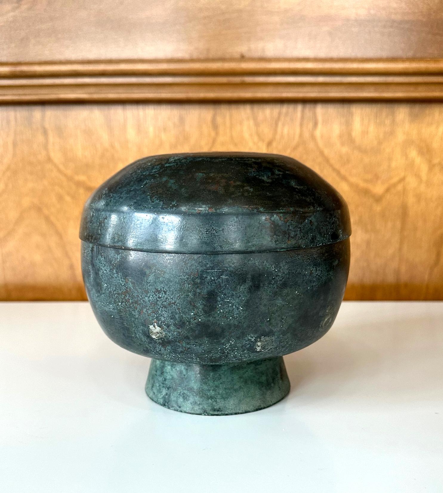 A bronze bowl shape vessel with fitted lid from Korean dated to 15-16th century (early Joseon Dynasty). In an elegant minimalistic form with thin wall and supported by a high foot ring, this flat top bowl was likely reserved for ritual use. The